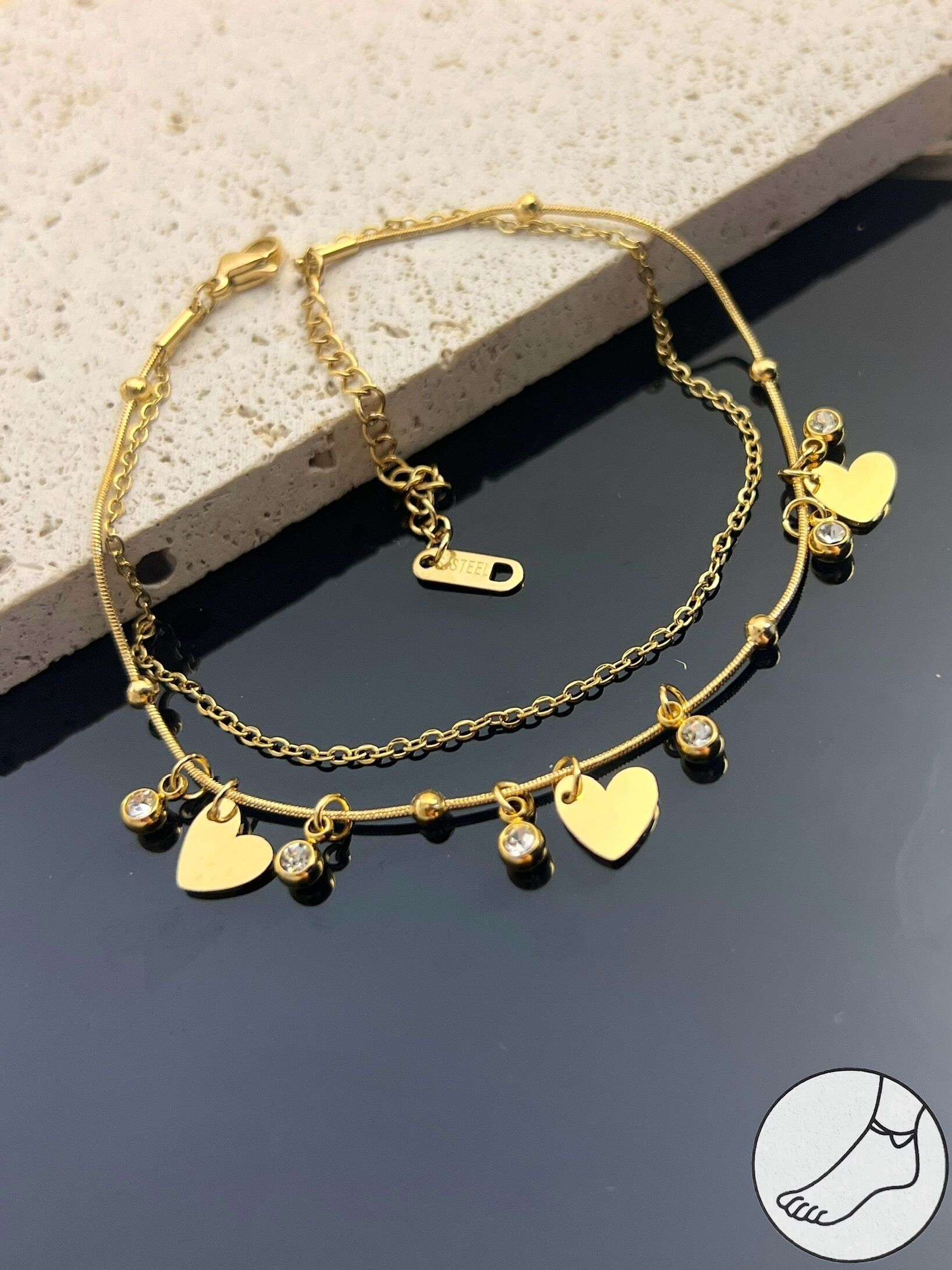 Cadena de tobillo de acero de doble vuelta decorada con un dije de corazón.