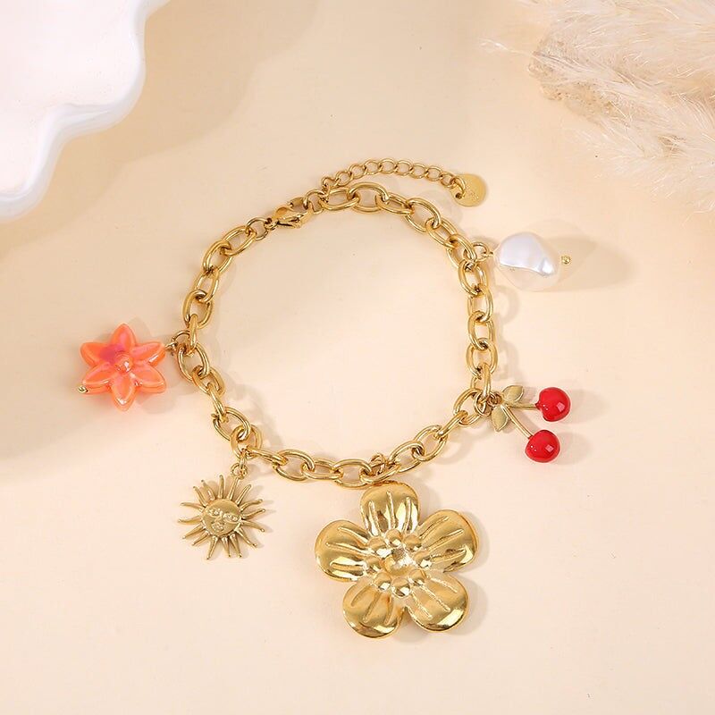 Bracciale in oro con ciondoli a forma di fiore di ciliegio, sole e perla