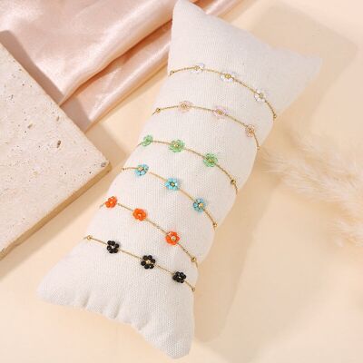 Conjunto de 6 pulseras de flores de colores sobre cojín.