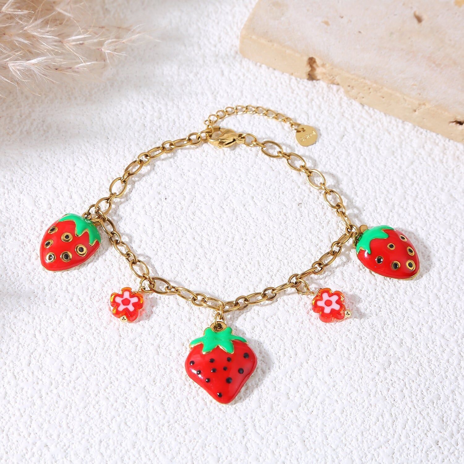 Bracciale a catena in oro con ciondoli a forma di fragola e fiore