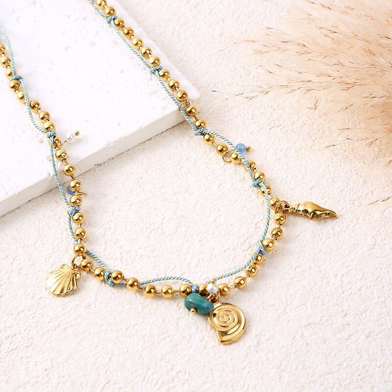 Collana con catena in oro con cordino blu, ciondoli a conchiglia e pietra verde smeraldo