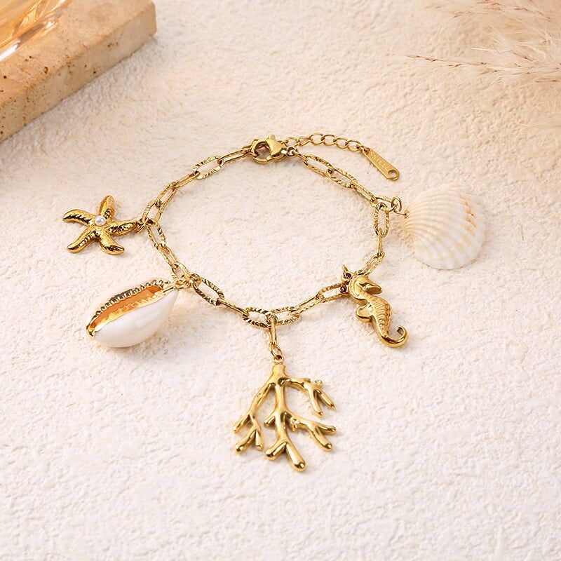 Bracciale a catena in oro con ciondoli a forma di cavalluccio marino, corallo e conchiglia