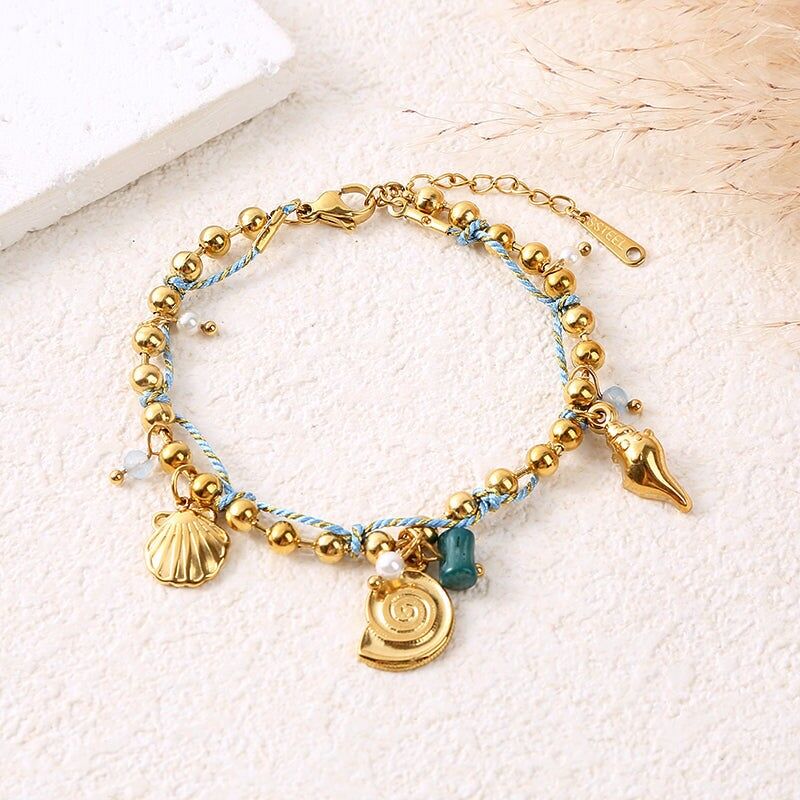 Bracciale a catena con perline dorate, cordino blu, ciondoli a forma di conchiglia e pietra verde smeraldo