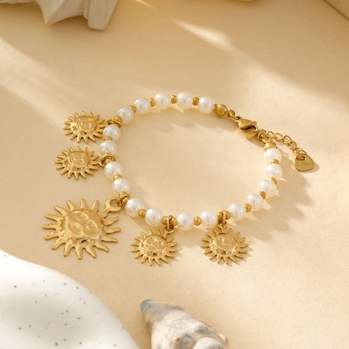 Bracciale di perle bianche e oro con ciondoli a forma di sole