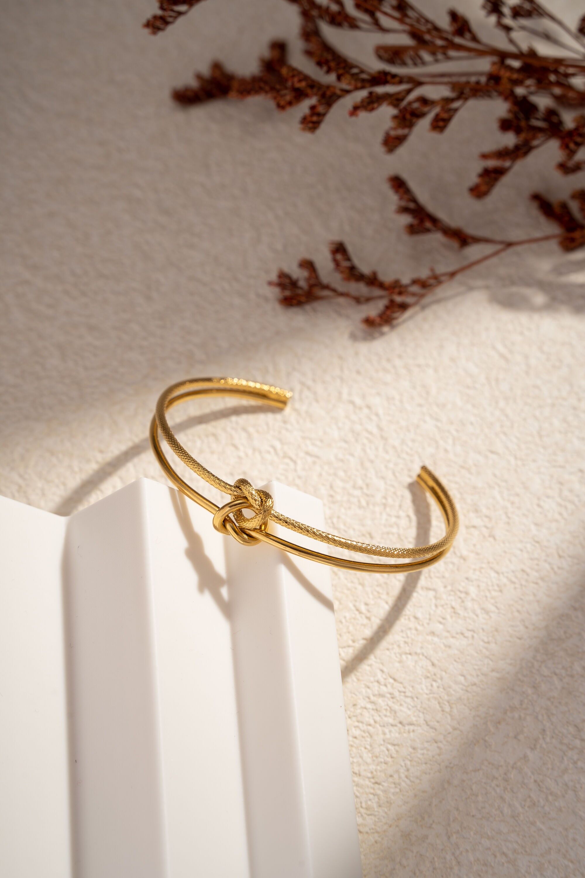 Bracciale rigido minimalista in oro con raffinato nodo centrale