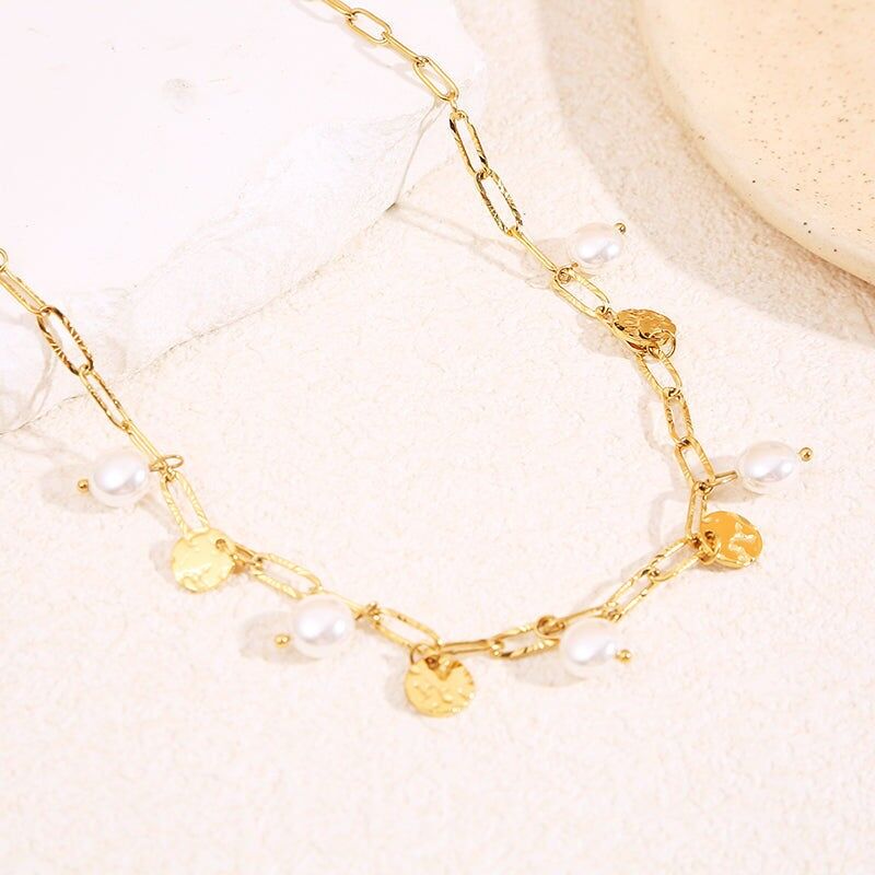 Collana lunga con catena in oro, ornata da pendenti a medaglione martellati e perle bianche pendenti