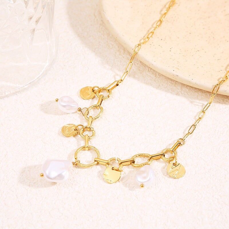 Collana a maglie color oro con anelli testurizzati alternati e barre lisce, impreziosita da pendenti a medaglione martellati e perle bianche irregolari