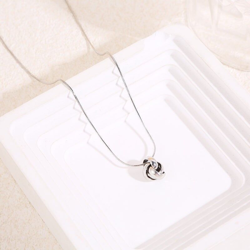 Collana con catena a serpente in argento pregiato e ciondolo a forma di nodo intagliato in rilievo