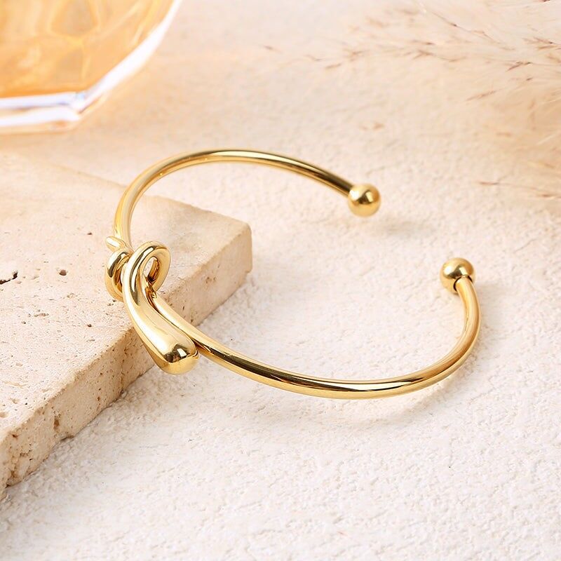 Bracciale rigido regolabile in oro con nodo centrale scolpito e estremità a sfera