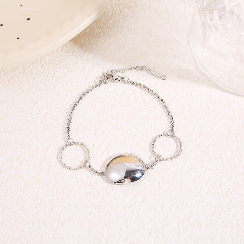 Fine silver chain bracelet with two textured rings and a central domed mirror-finished disc