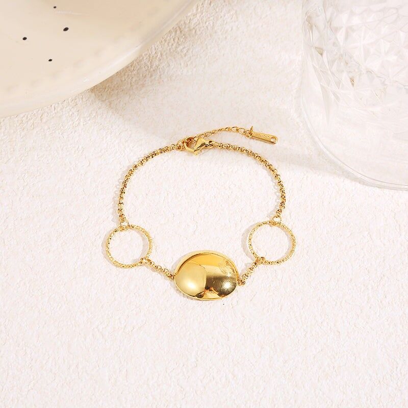 Feines Goldkettenarmband mit zwei strukturierten Ringen und einer zentralen gewölbten, hochglanzpolierten Scheibe