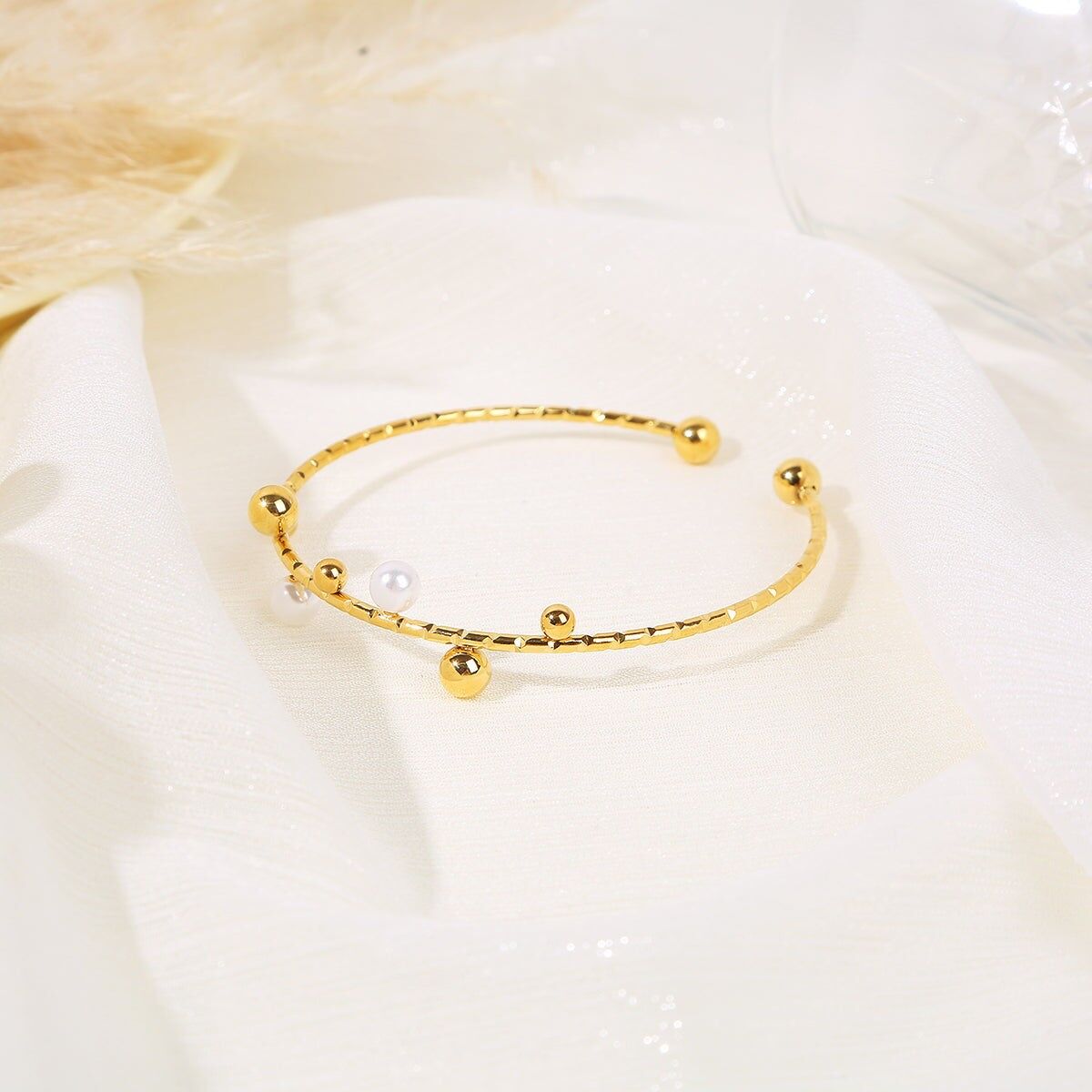 Offener goldener Armreif, verziert mit Gold- und Perlenperlen mit Goldperlen an den Enden