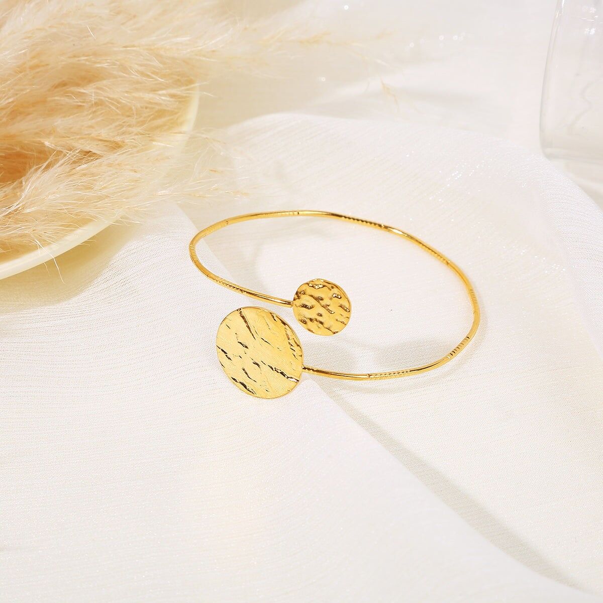 Verstellbarer goldener Armreif, vorne gekreuzt, mit Kreisen in Wellenoptik an den Enden