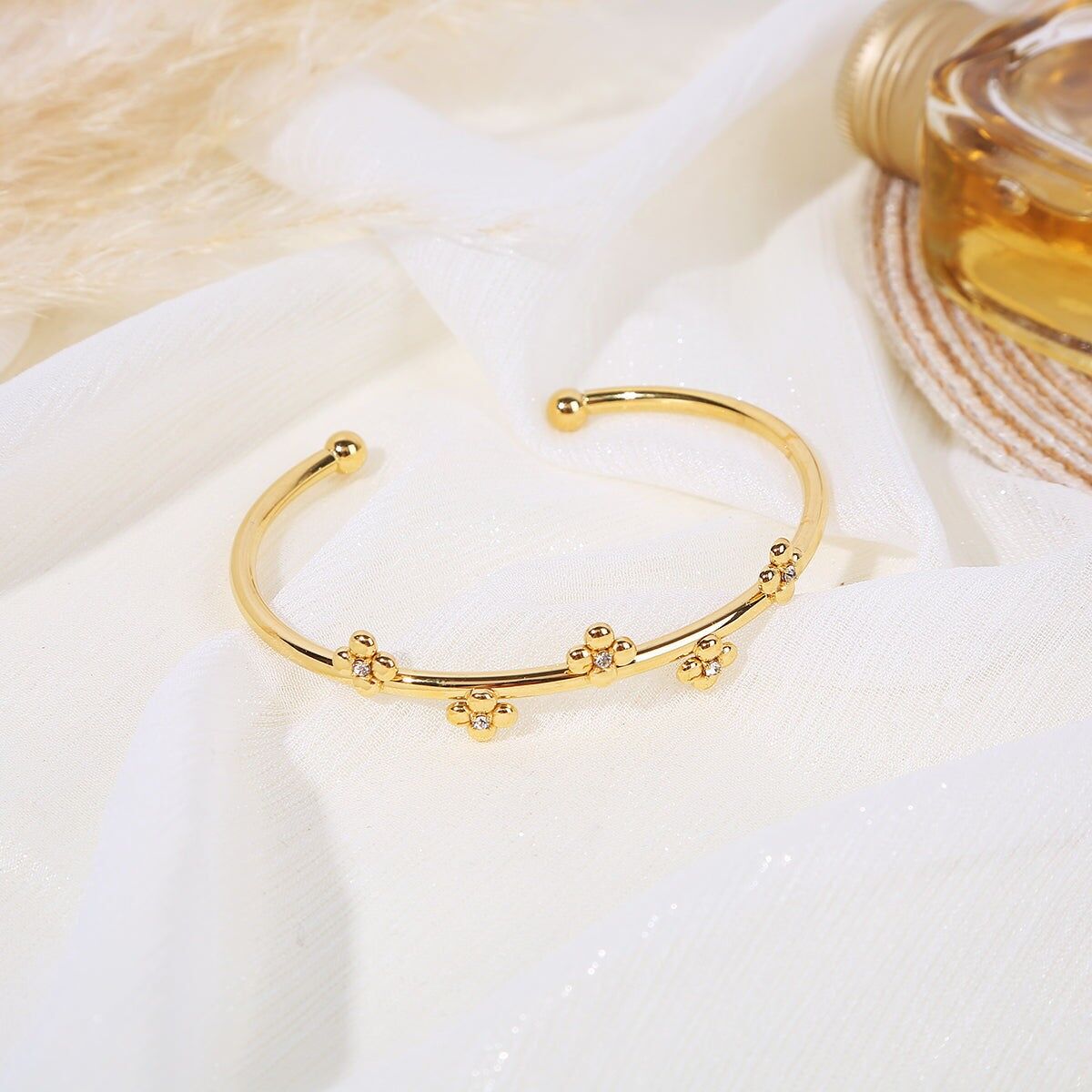 Offener goldener Armreif mit goldenen Perlen an den Enden, verziert mit Blumen aus Kreisen mit Strasssteinen