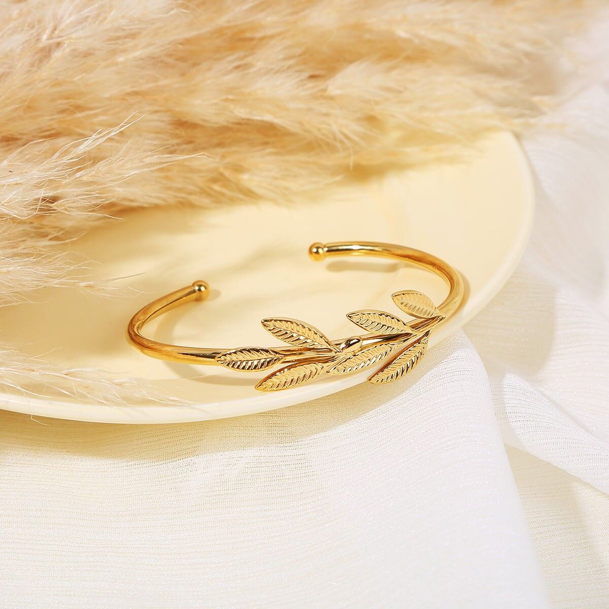 Offener goldener Armreif, verziert mit geformten Blättern mit goldenen Perlen an den Enden