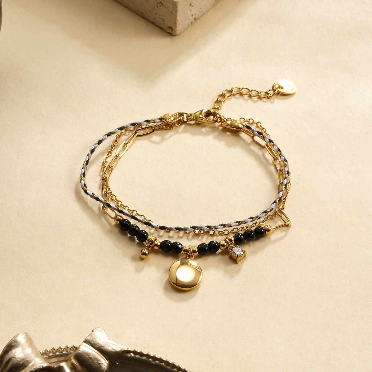 Bracciale a doppia catena e corda intrecciata con pietre nere e ciondolo rotondo liscio, strass