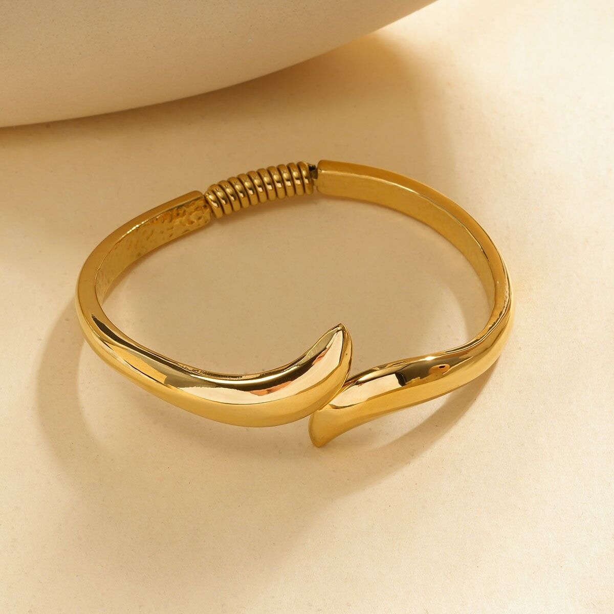 Bracciale rigido quadrato arrotondato in oro aperto con estremità appuntite e affusolate e dettaglio a spirale sul retro