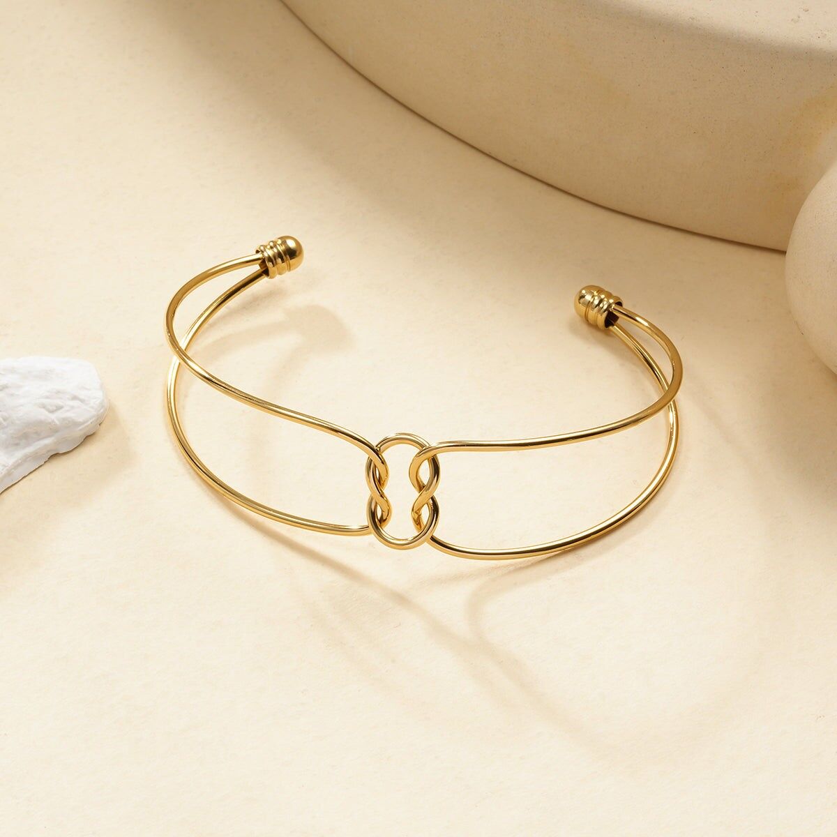 Bracciale rigido minimalista con anelli intrecciati in oro