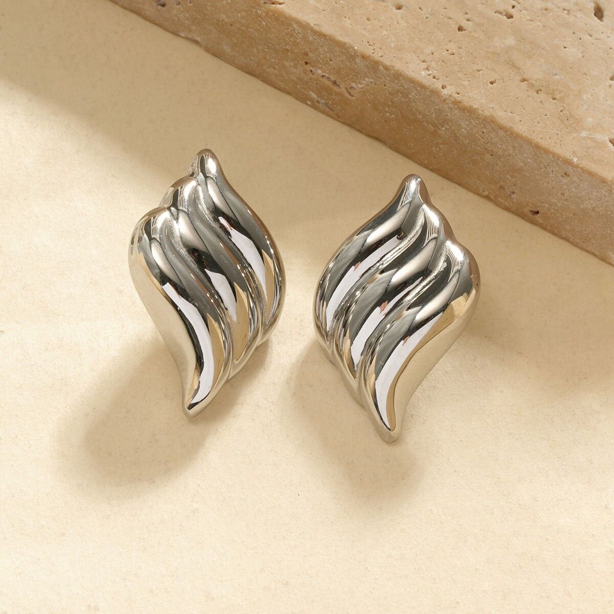 Boucles d’oreilles argentées en forme de flamme ondulée à relief bombé finition miroir