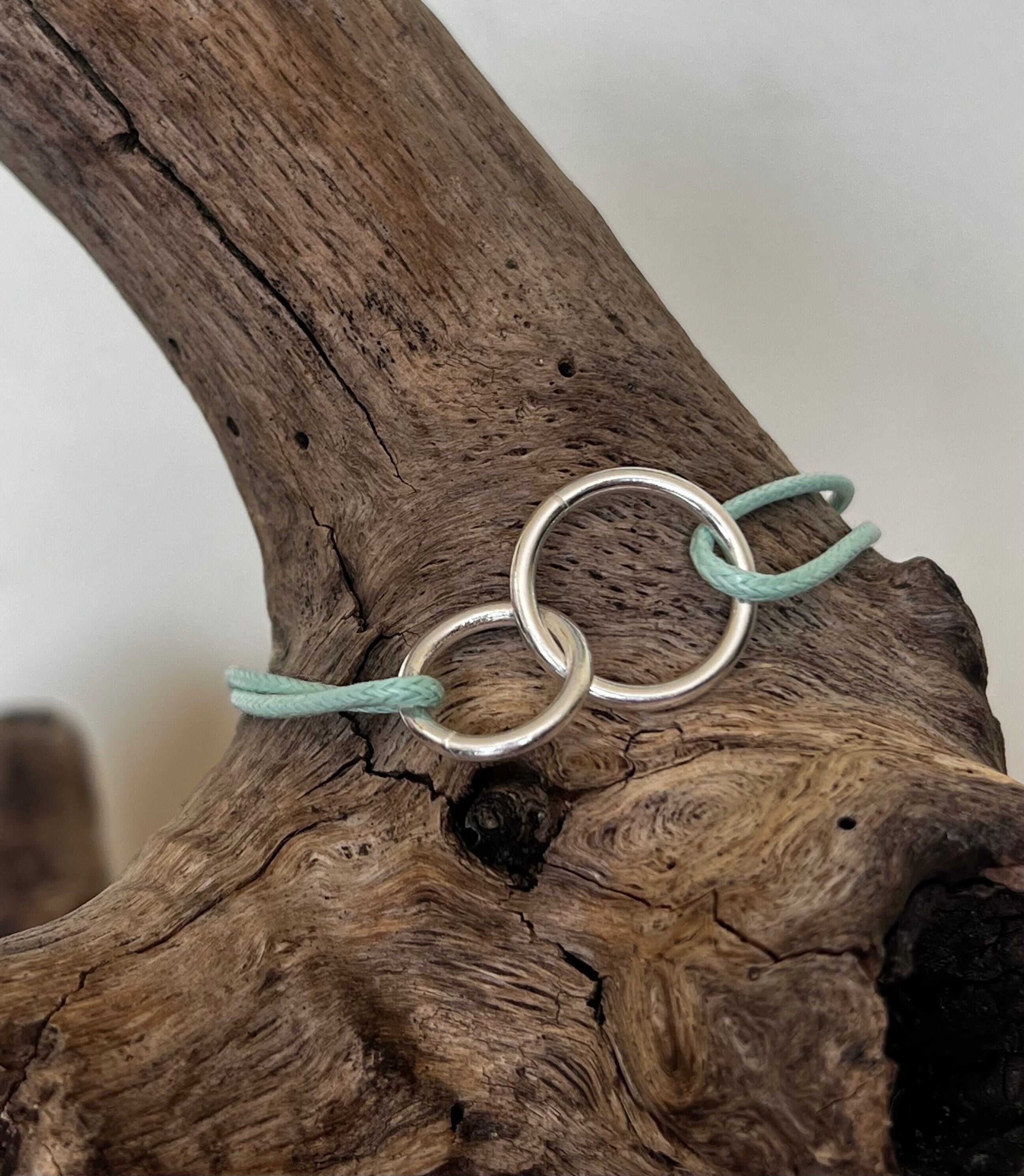 Pulsera en forma de anillos y cordón entrelazados