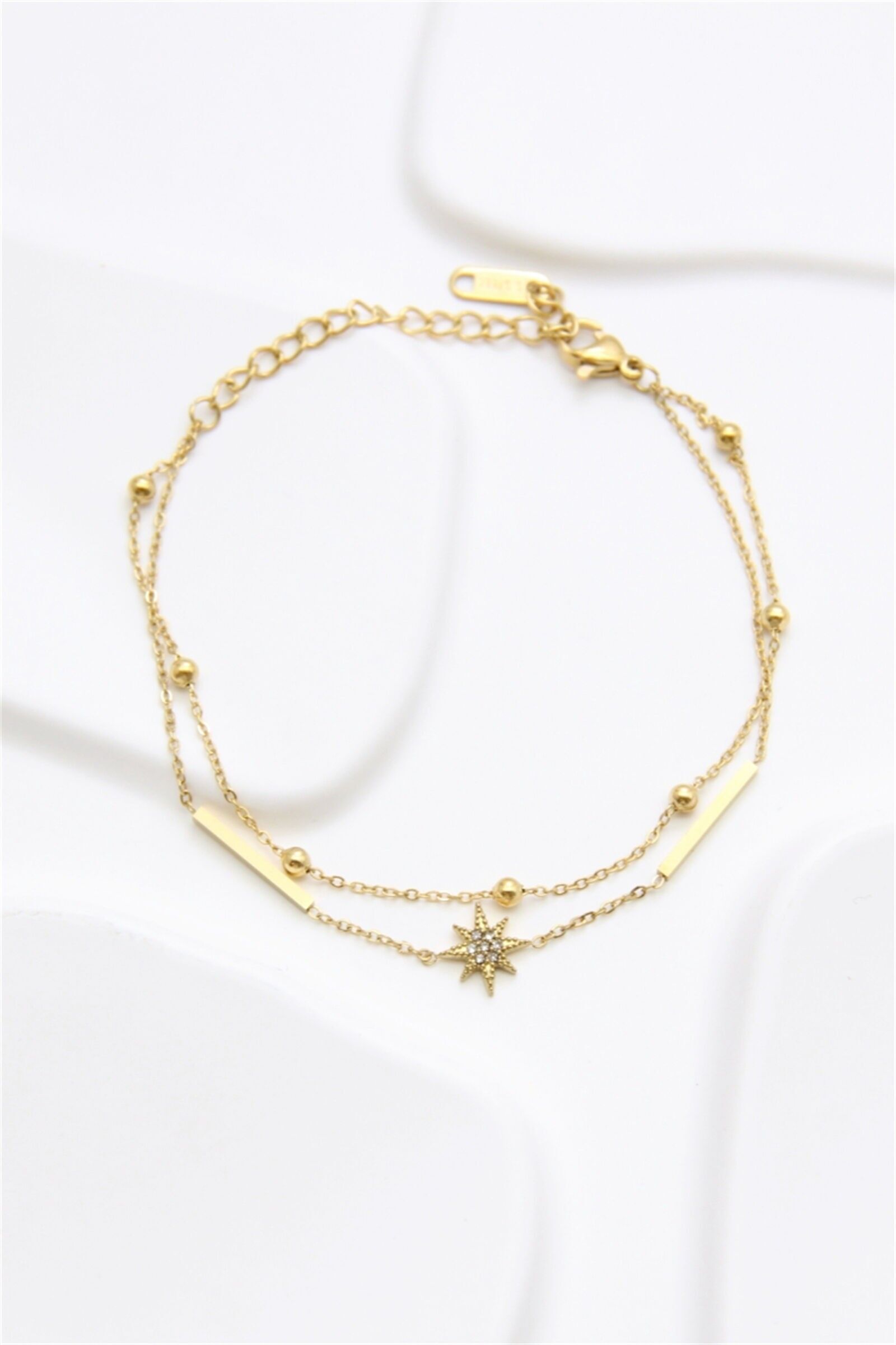 Pulse, eine doppelte goldene Edelstahlkette mit glänzenden Sternen und minimalistischen Stäben.