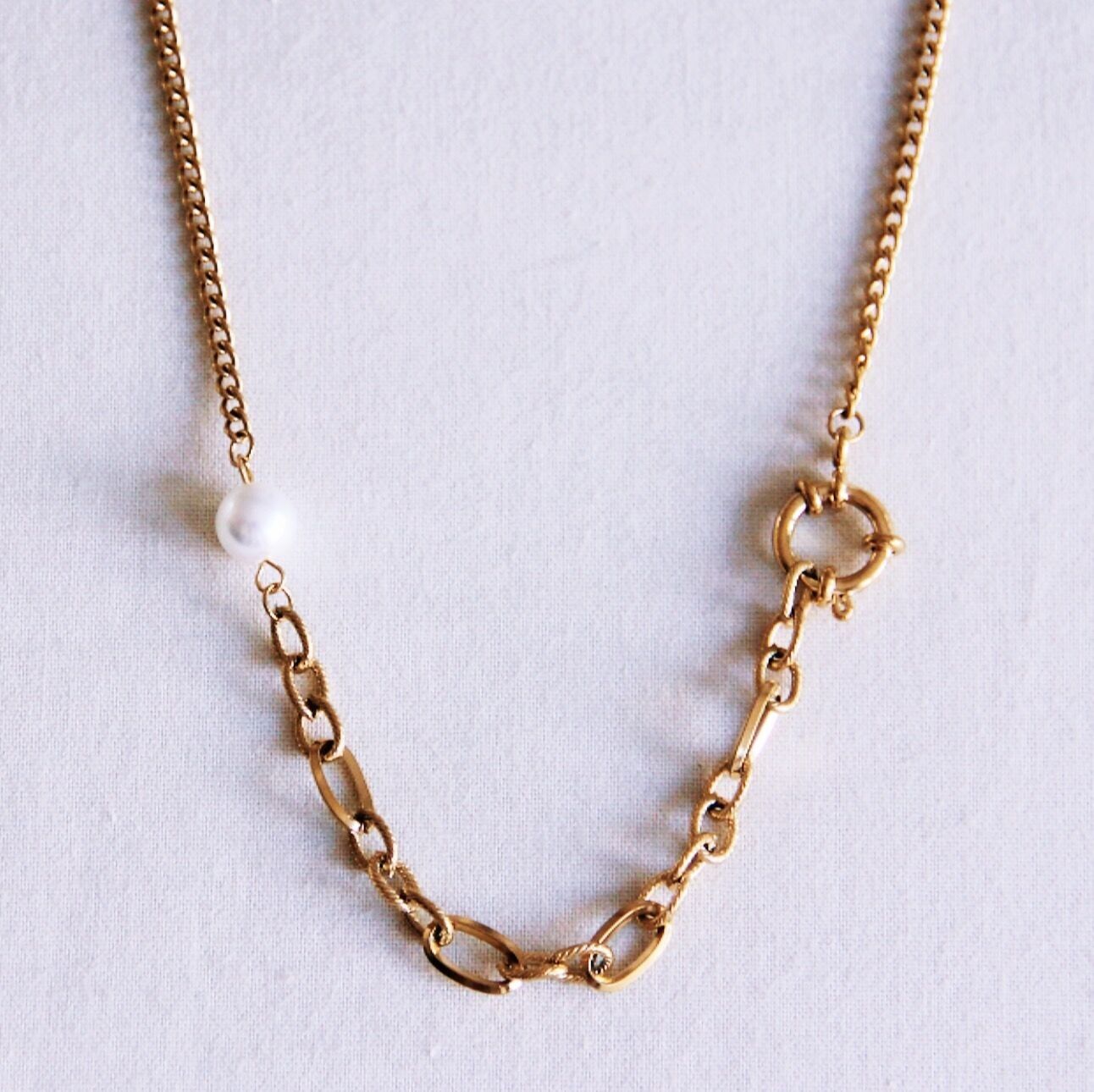 Cadena de eslabones con cierre redondo, perla y eslabones decorados.