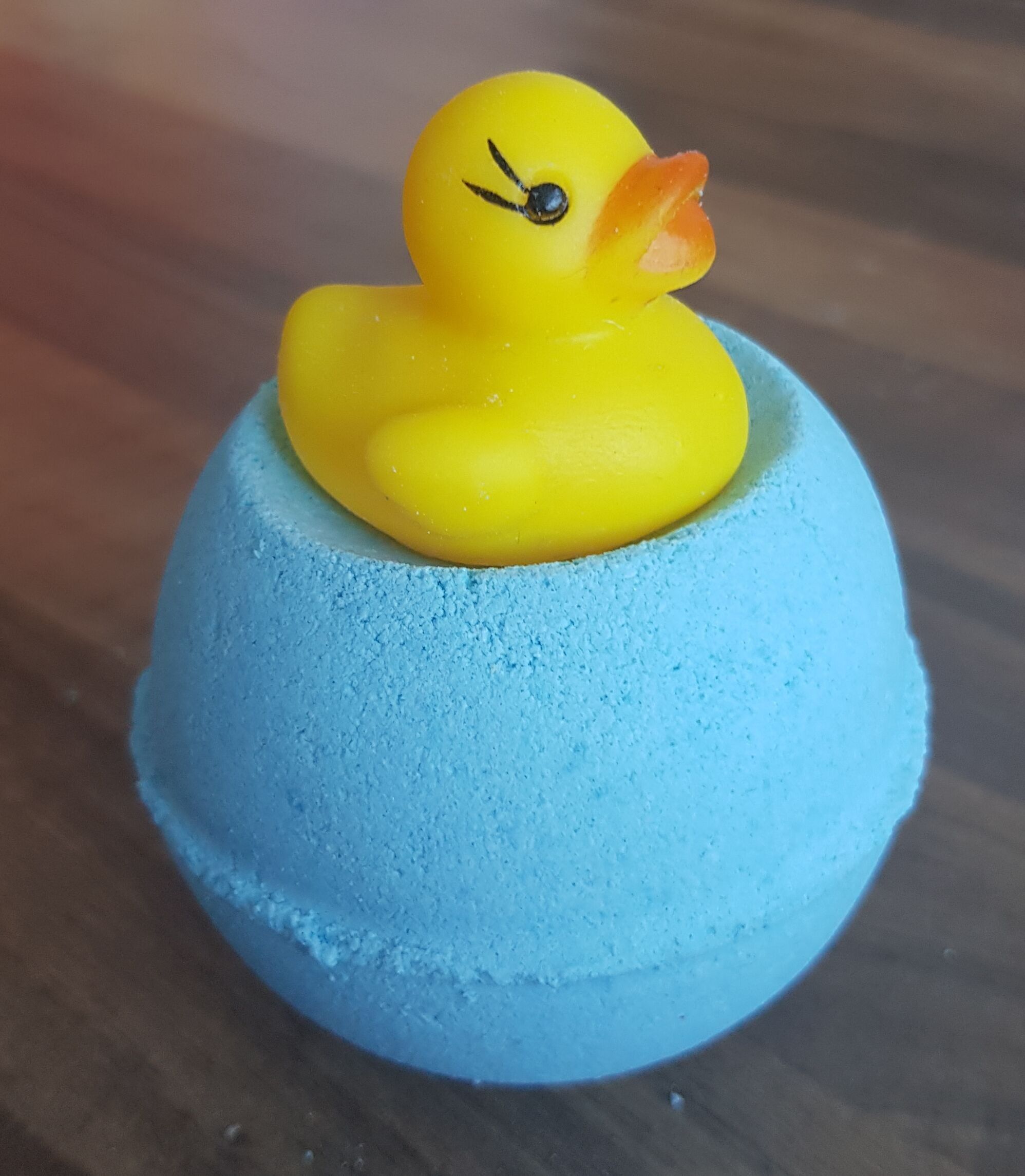 Bombe de bain bleue avec un petit canard en caoutchouc posé dessus