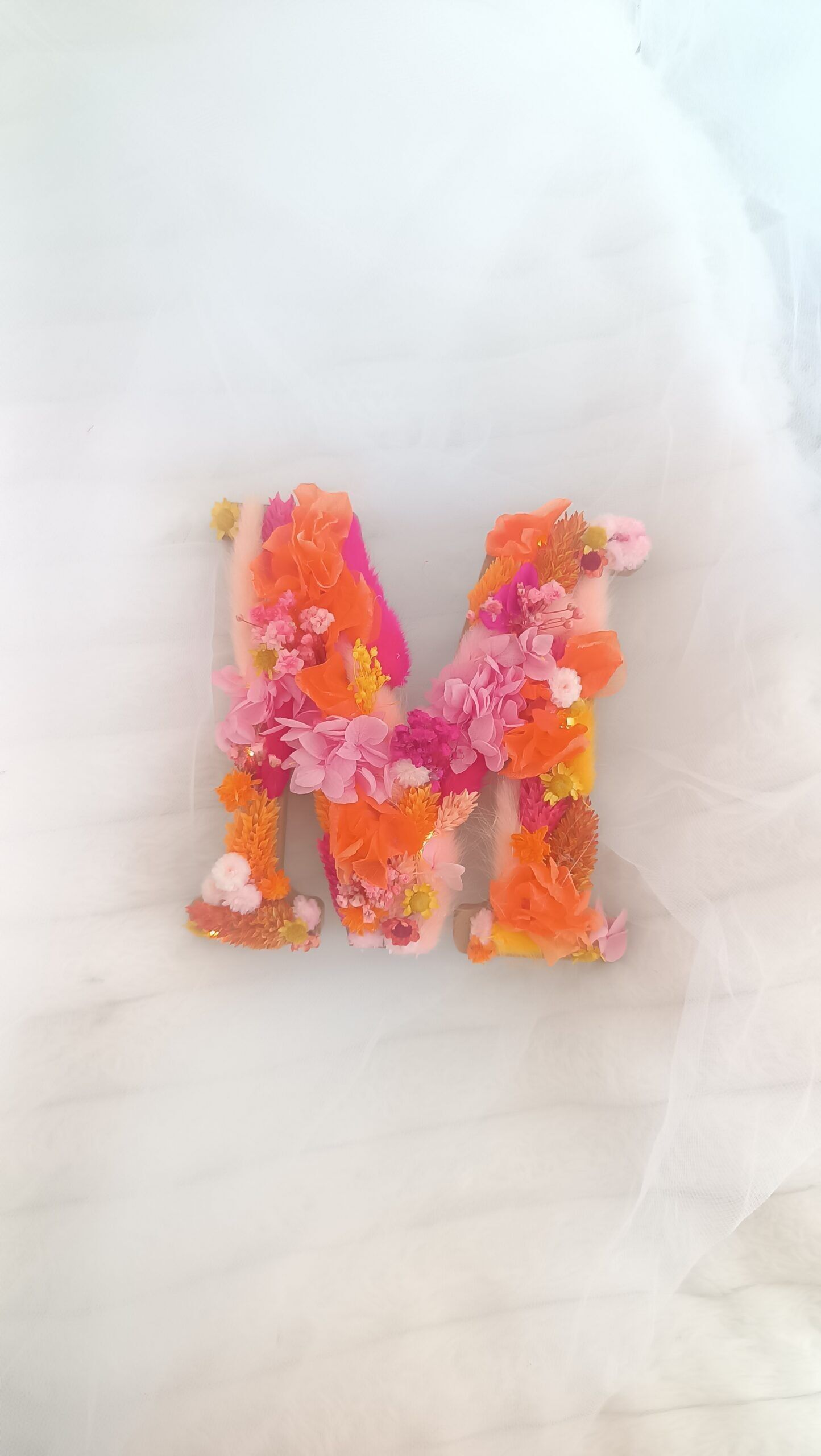 Letra floral en flores secas terracota fucsia y naranja