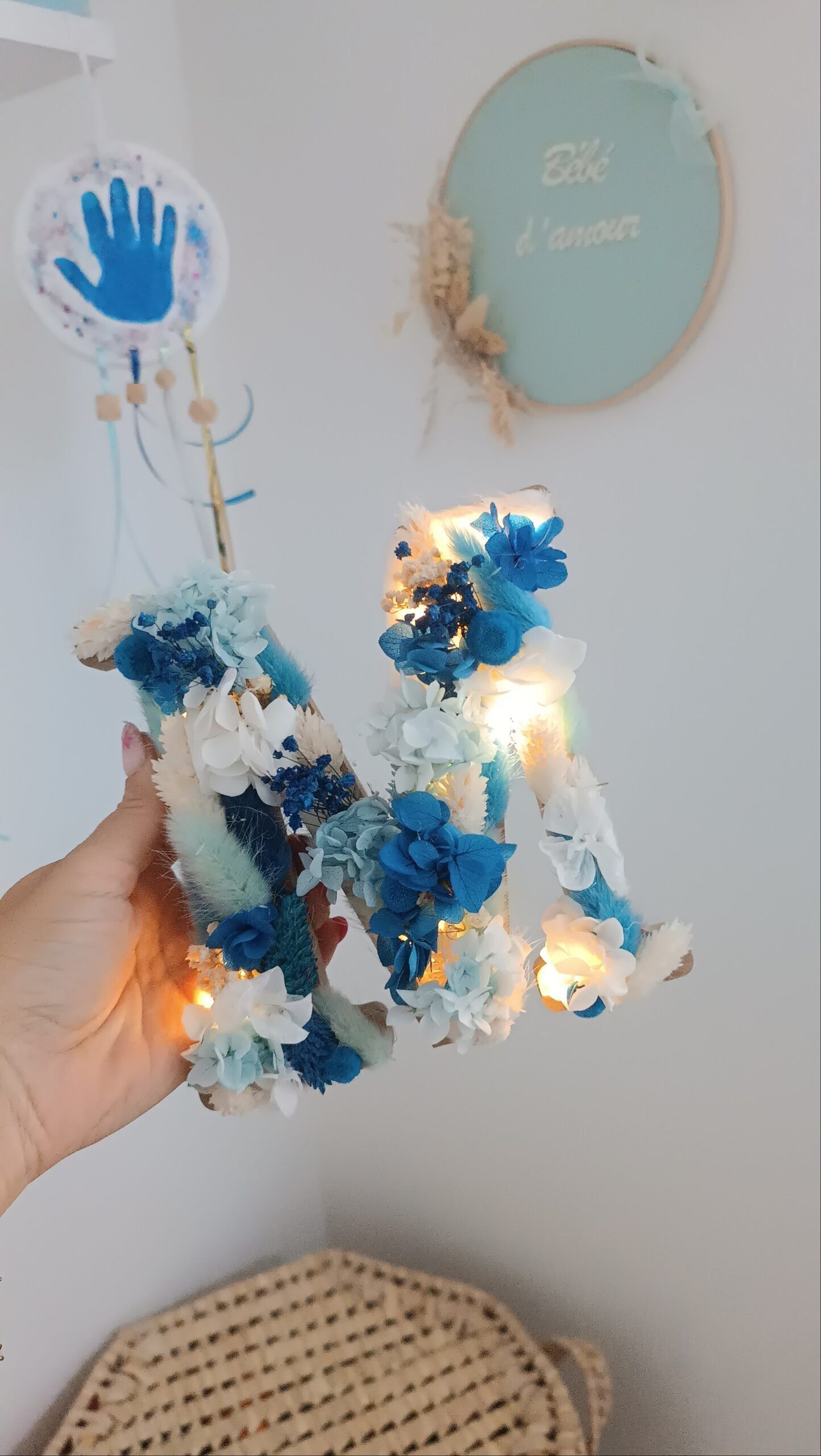 Letra floral en flores secas en tonos azules y blancos.