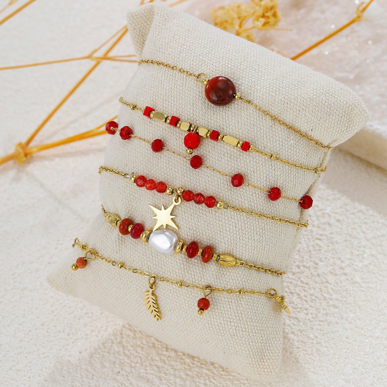 Set aus 6 farbenfrohen Armbändern mit roten Steinen auf einem Kissen