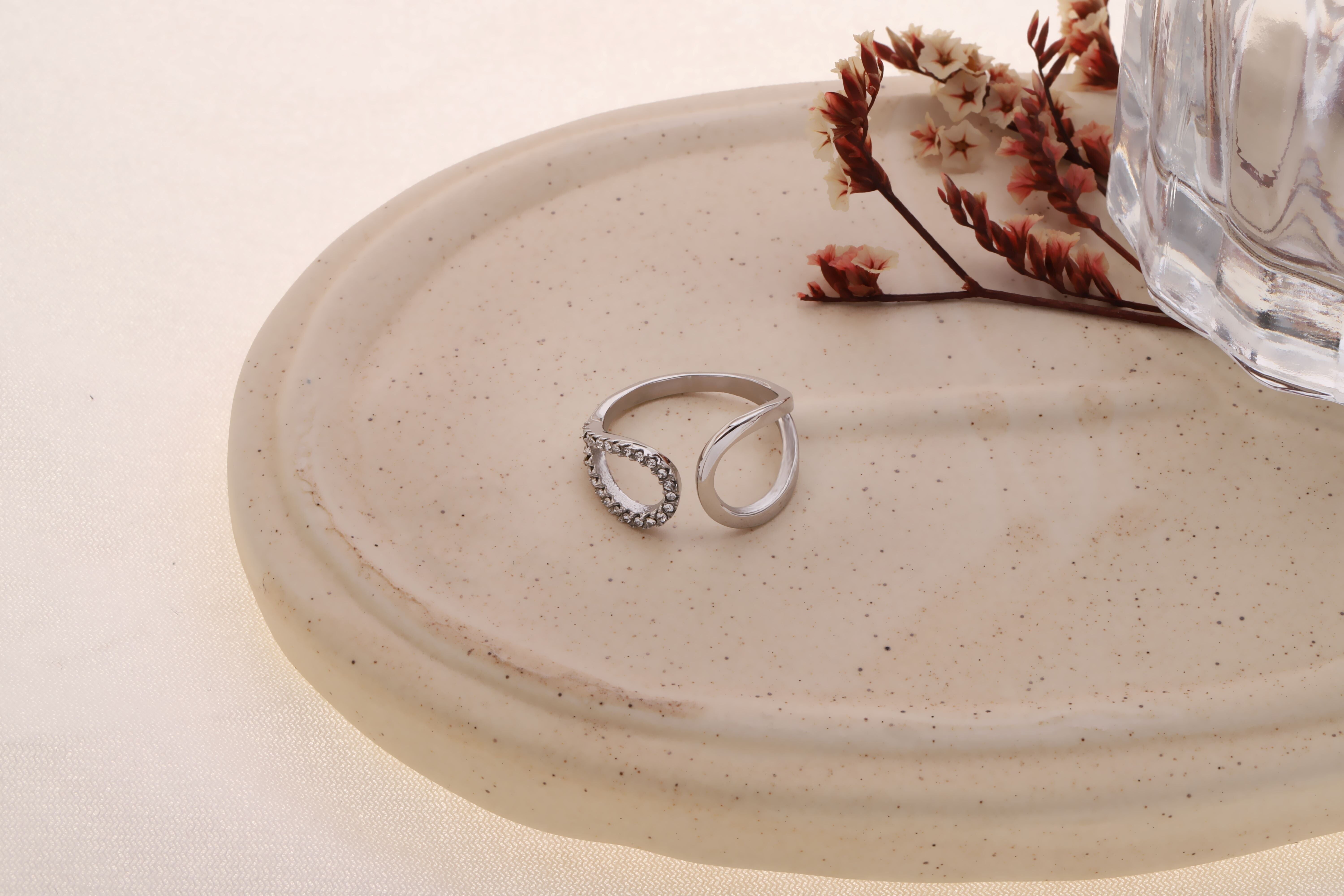 Anello in argento con apertura arrotondata nella parte anteriore, lato liscio e tempestato di strass.