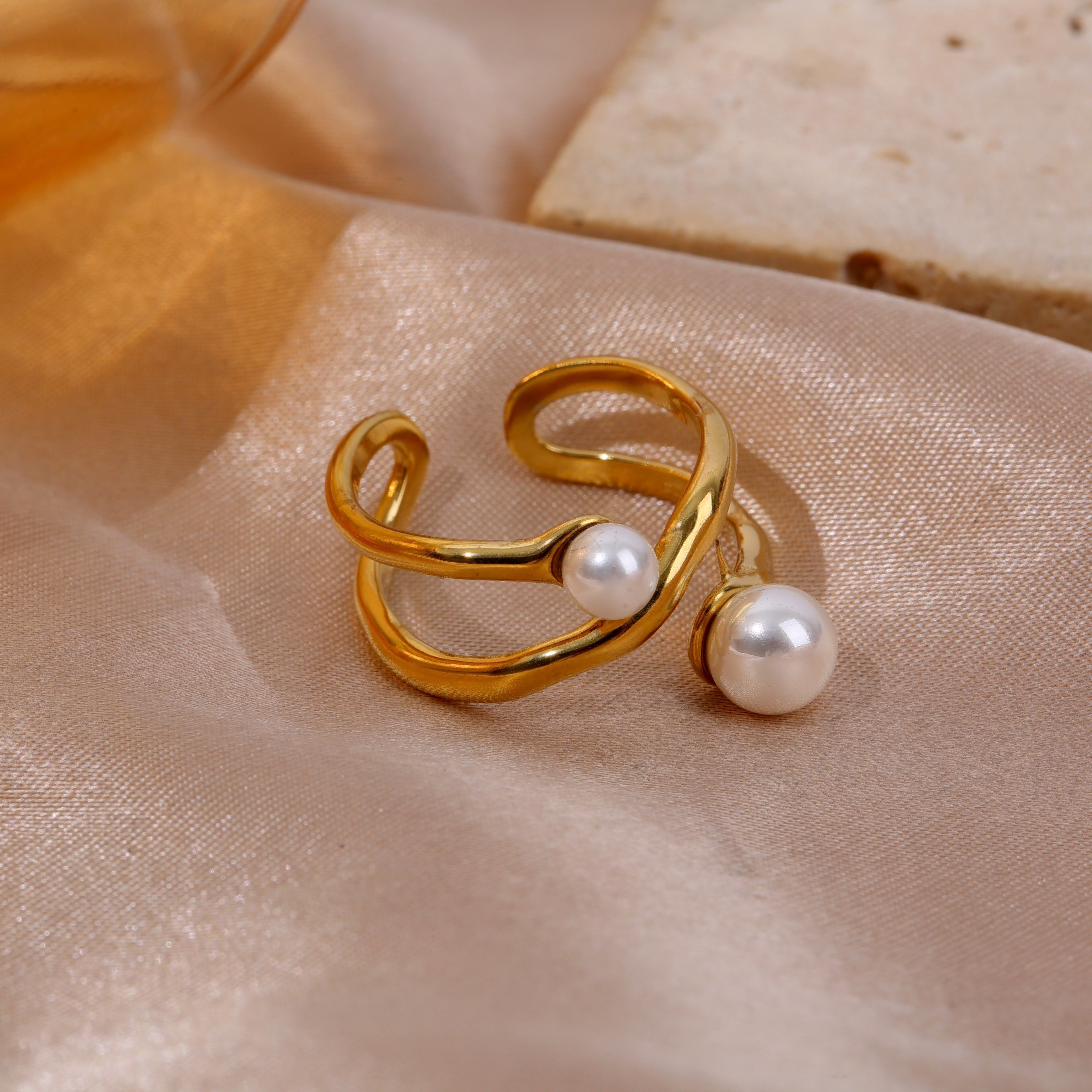 Anello regolabile in oro con doppi bracci incrociati e due perle intarsiate, apertura sul retro.