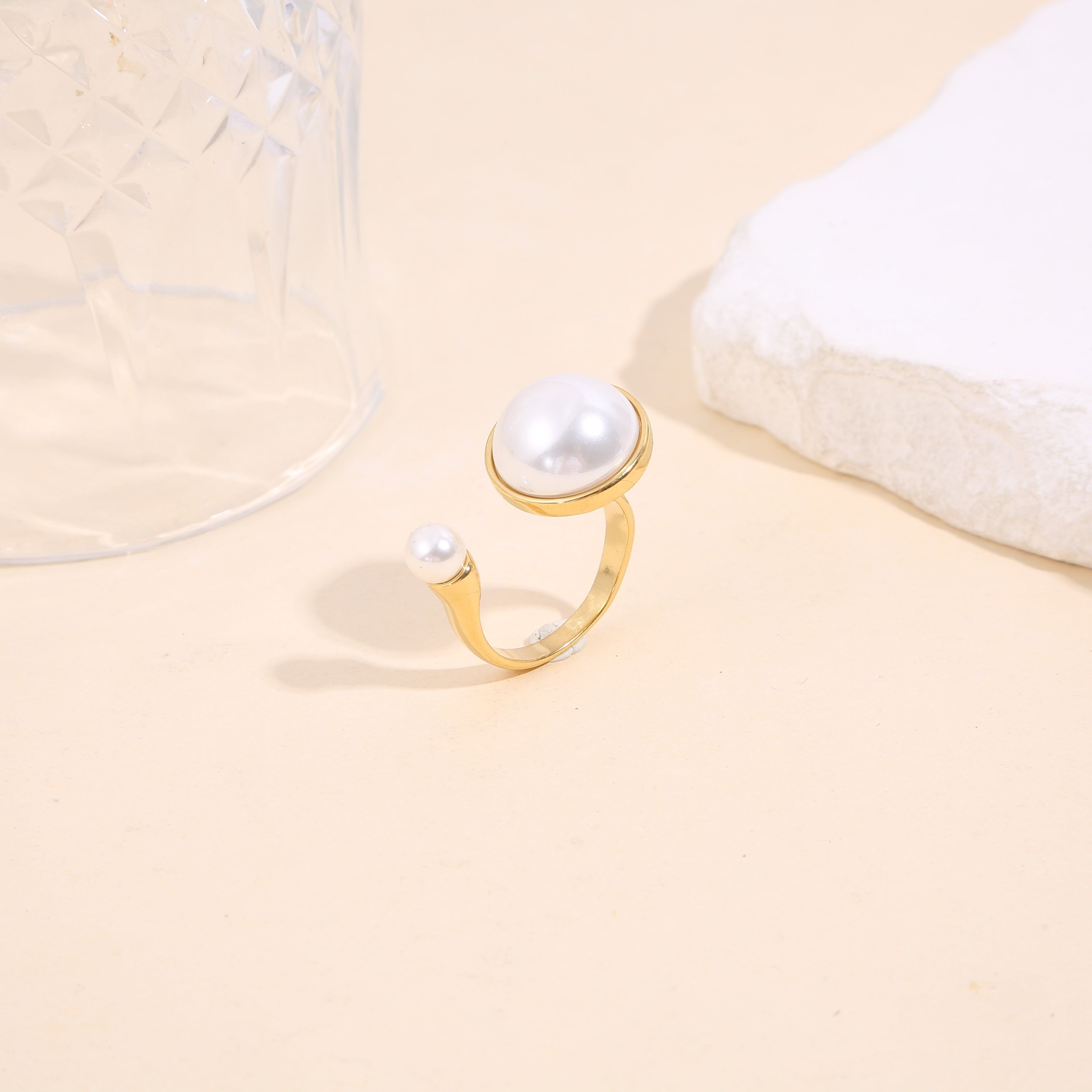 Anello color oro con apertura frontale, perla testurizzata con montatura liscia