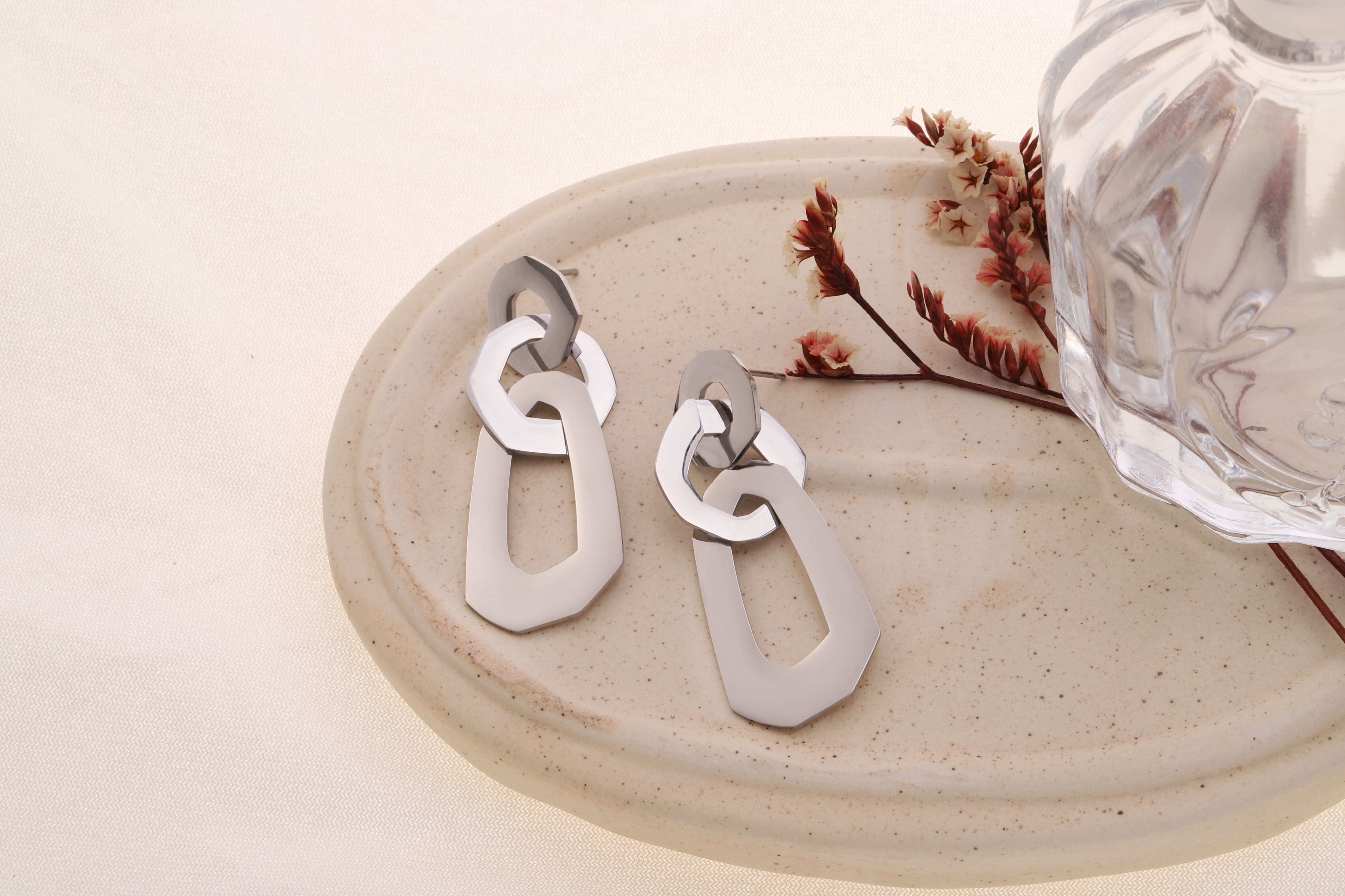 Trio di orecchini pendenti color argento con forme arrotondate collegate