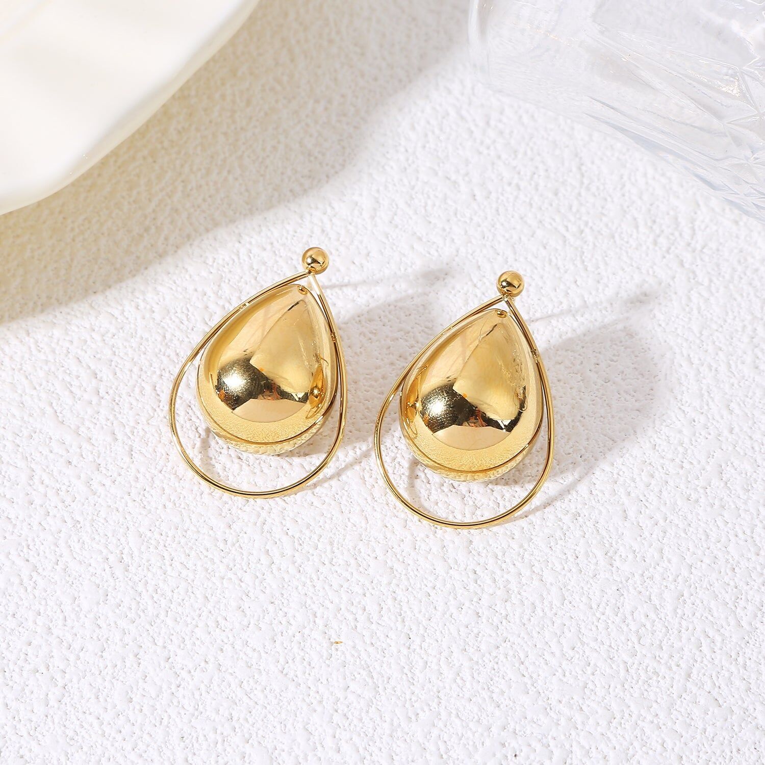 Orecchini pendenti in oro con forme bombate circondati da un sottile anello