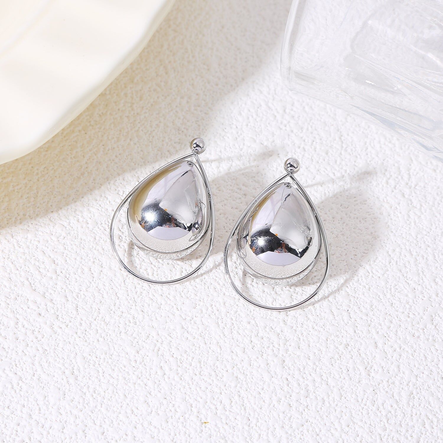 Orecchini pendenti in argento con forme bombate circondati da un sottile anello