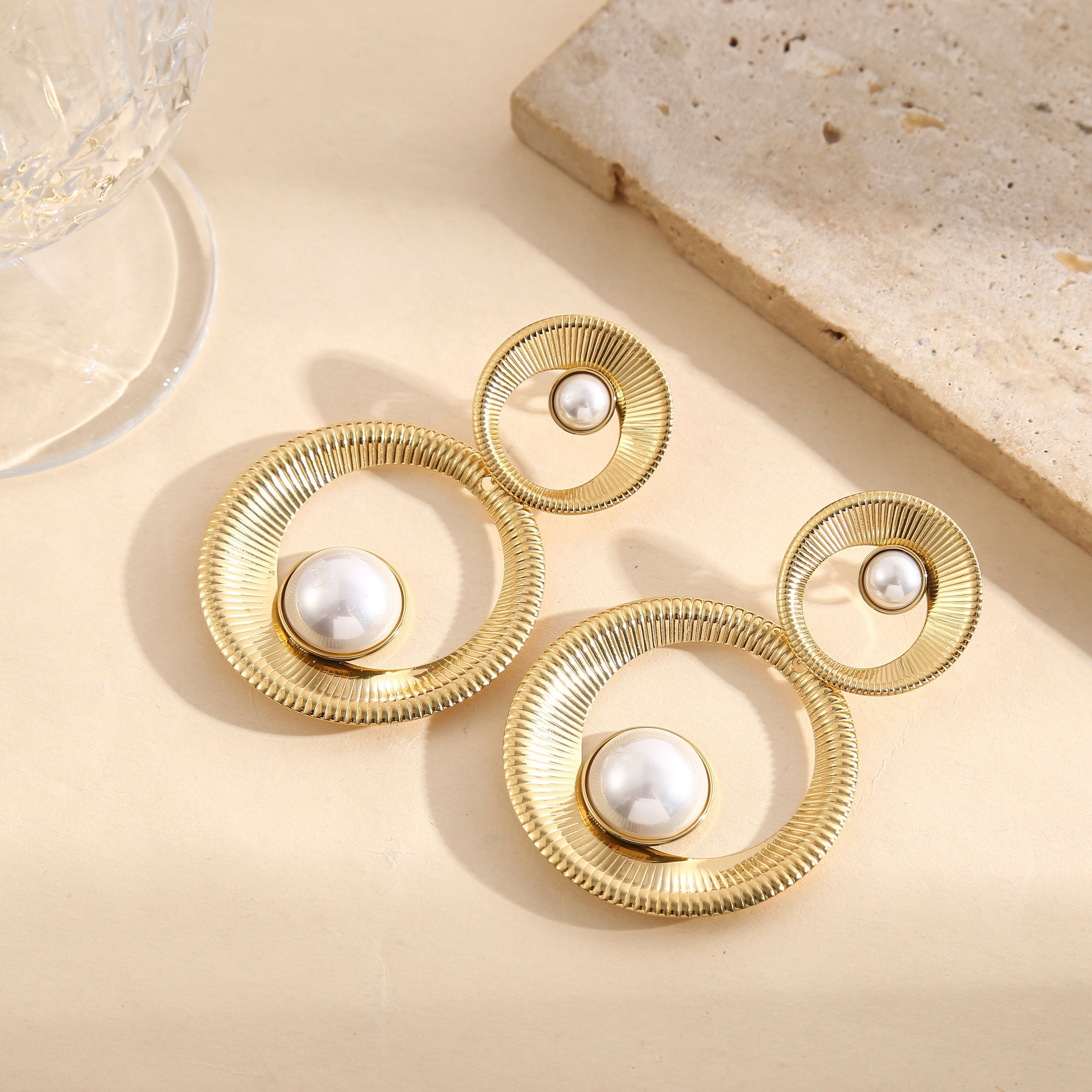 Orecchini pendenti color oro con due grandi cerchi testurizzati e perle