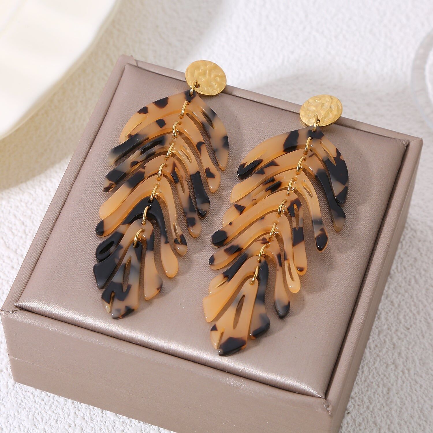 Orecchini pendenti color oro con foglie incernierate e una leggera stampa animalier