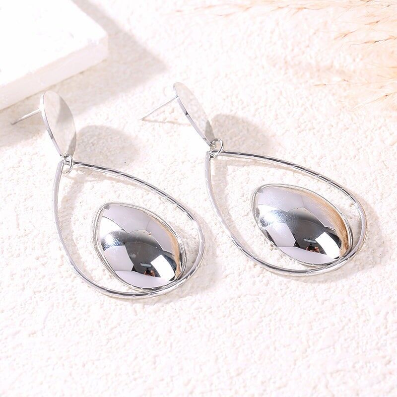 Orecchini pendenti in argento con forma a goccia traforata e medaglione centrale bombato con effetto specchio