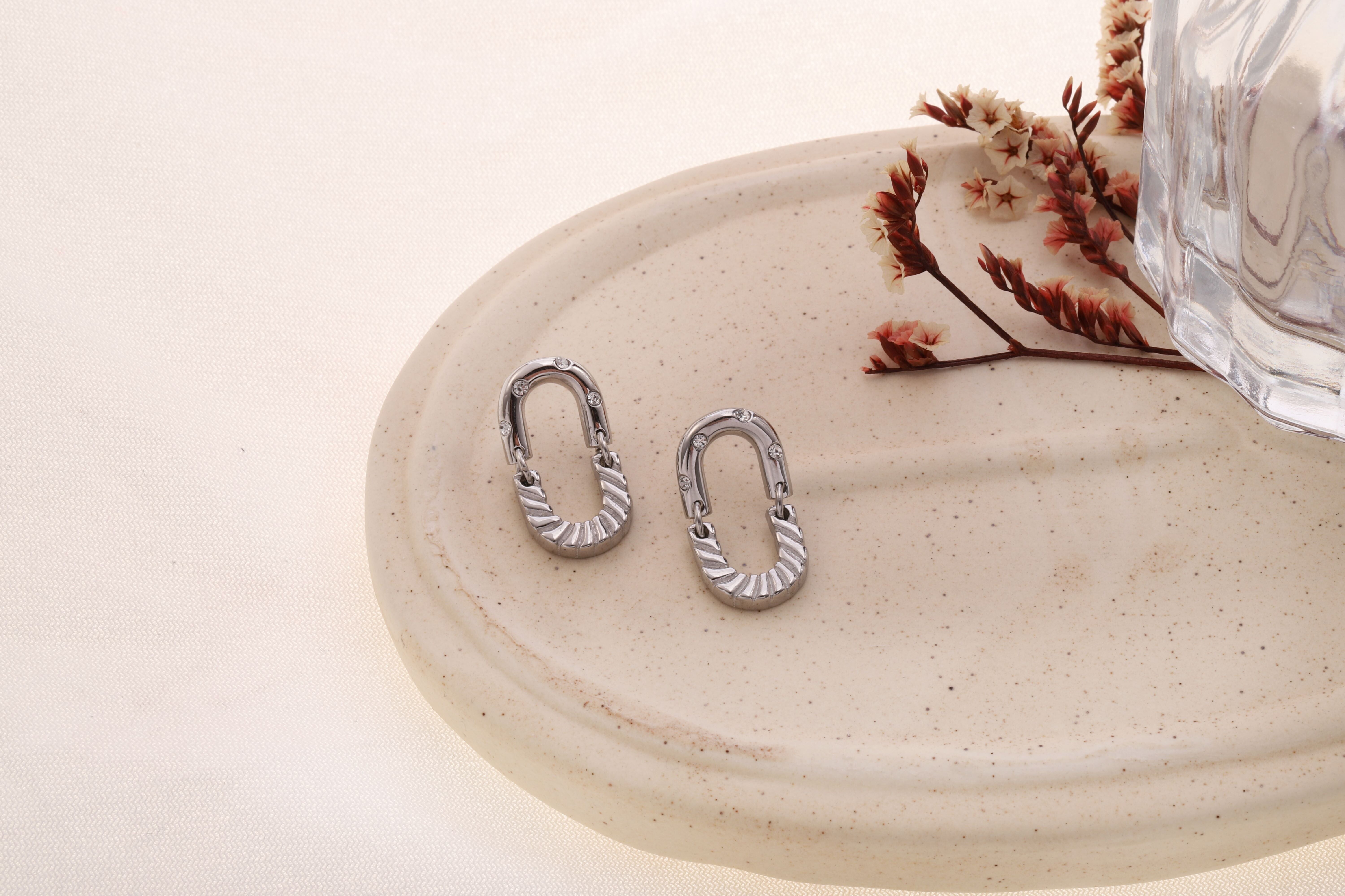 Orecchini ovali color argento con strass testurizzati ed effetto industriale