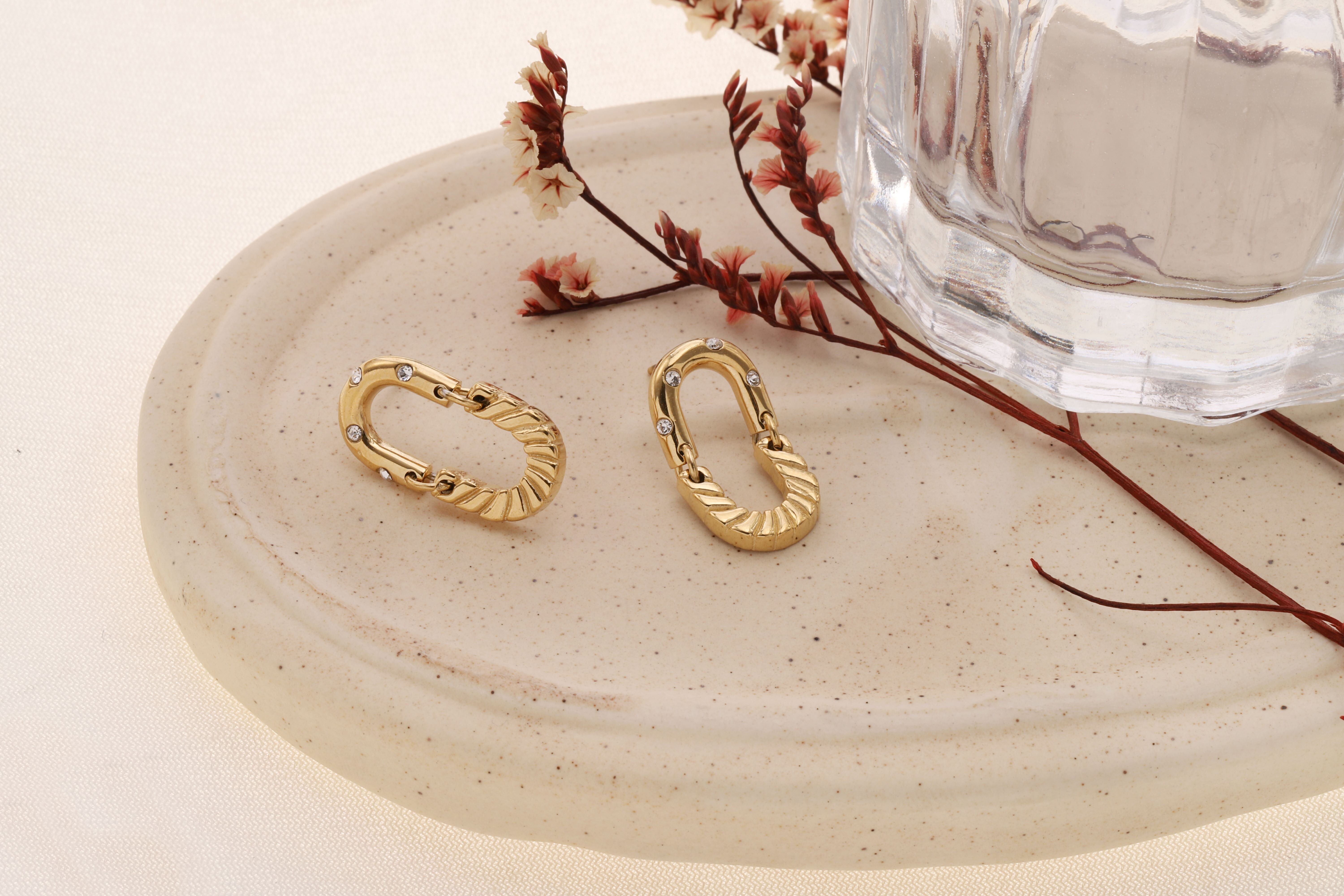 Orecchini ovali color oro con strass testurizzati ed effetto industriale