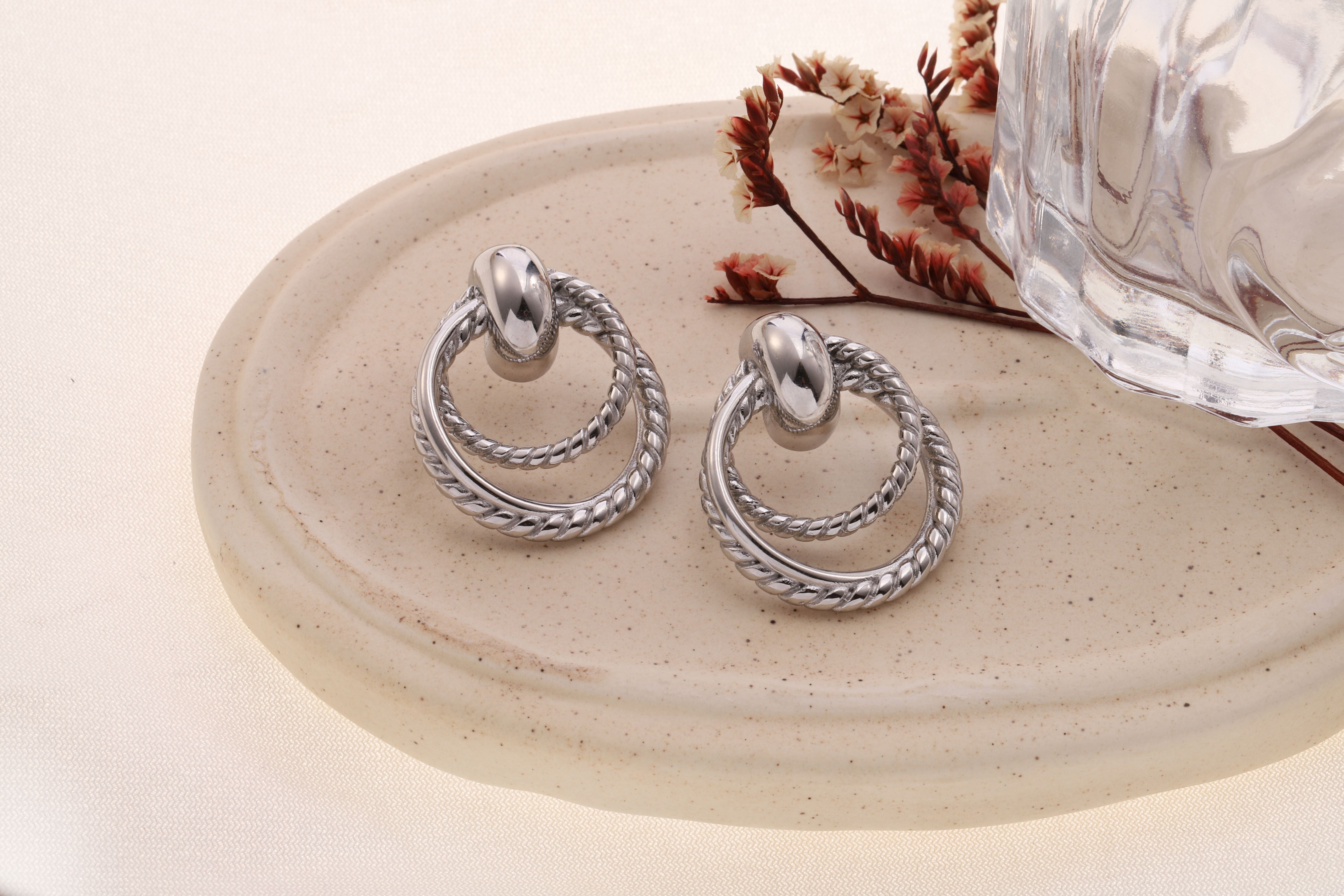 Orecchini a cerchio doppio ritorto in argento collegati da una maglia bombata lucida