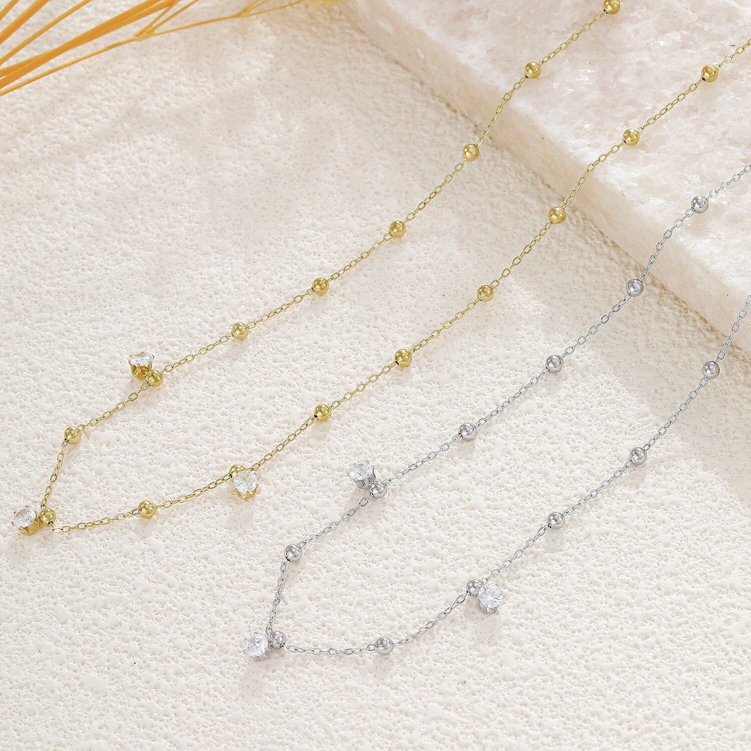 Collana color argento con catena sottile ornata da una perlina liscia e 3 strass sul davanti