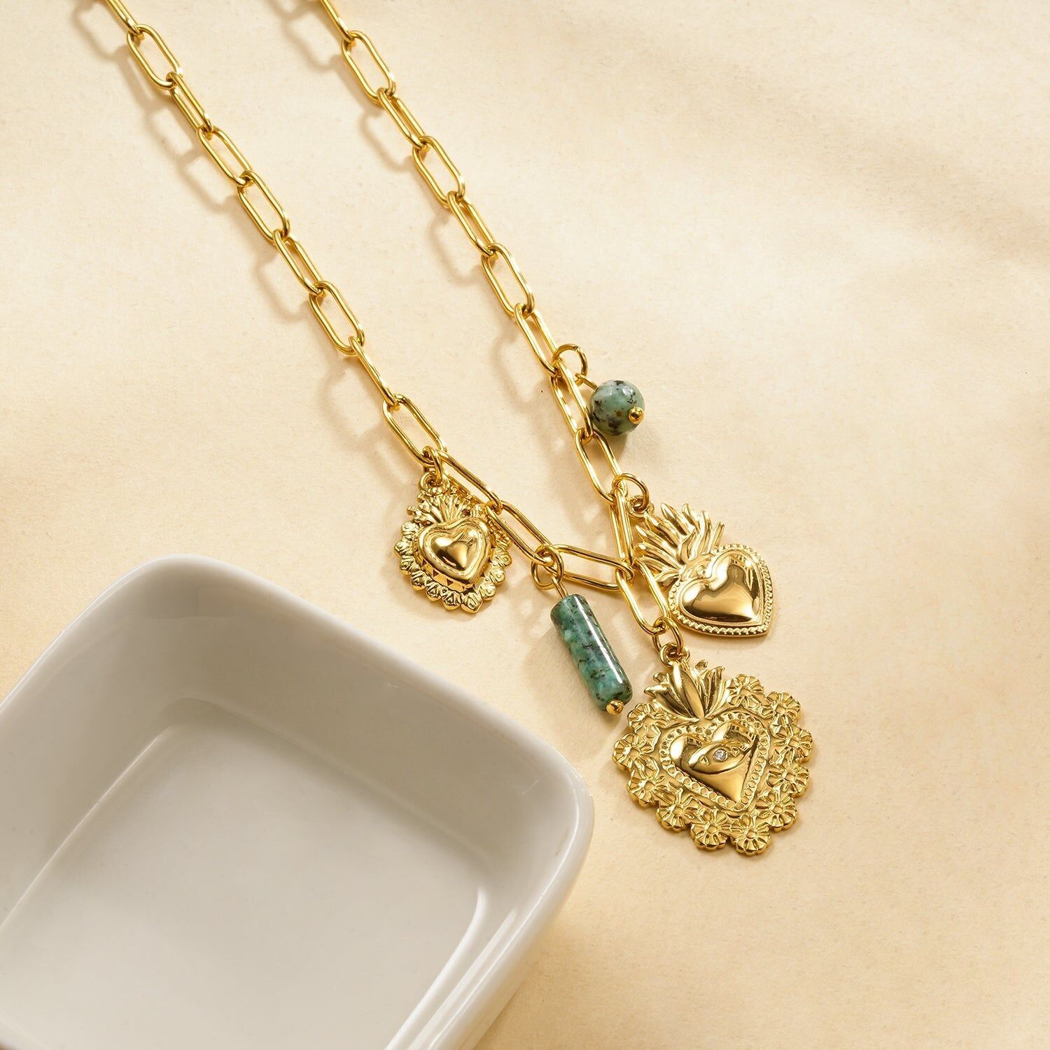 Goldene Halskette mit rechteckigen Gliedern, herzförmigen Votivanhängern und einem afrikanischen Türkisstein.