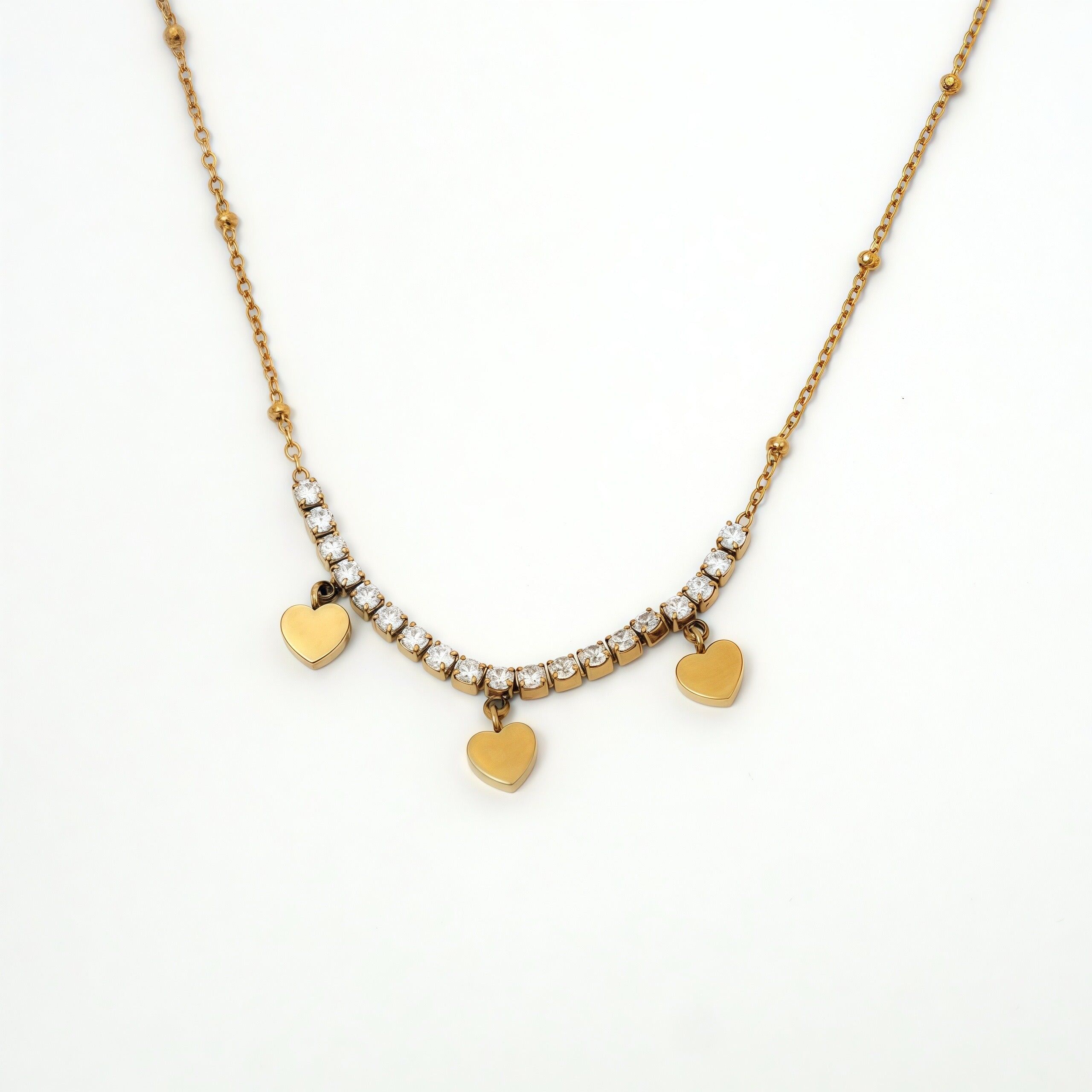 Collana color oro con catena sottile, una fila di strass e 3 nappe lisce a forma di cuore.