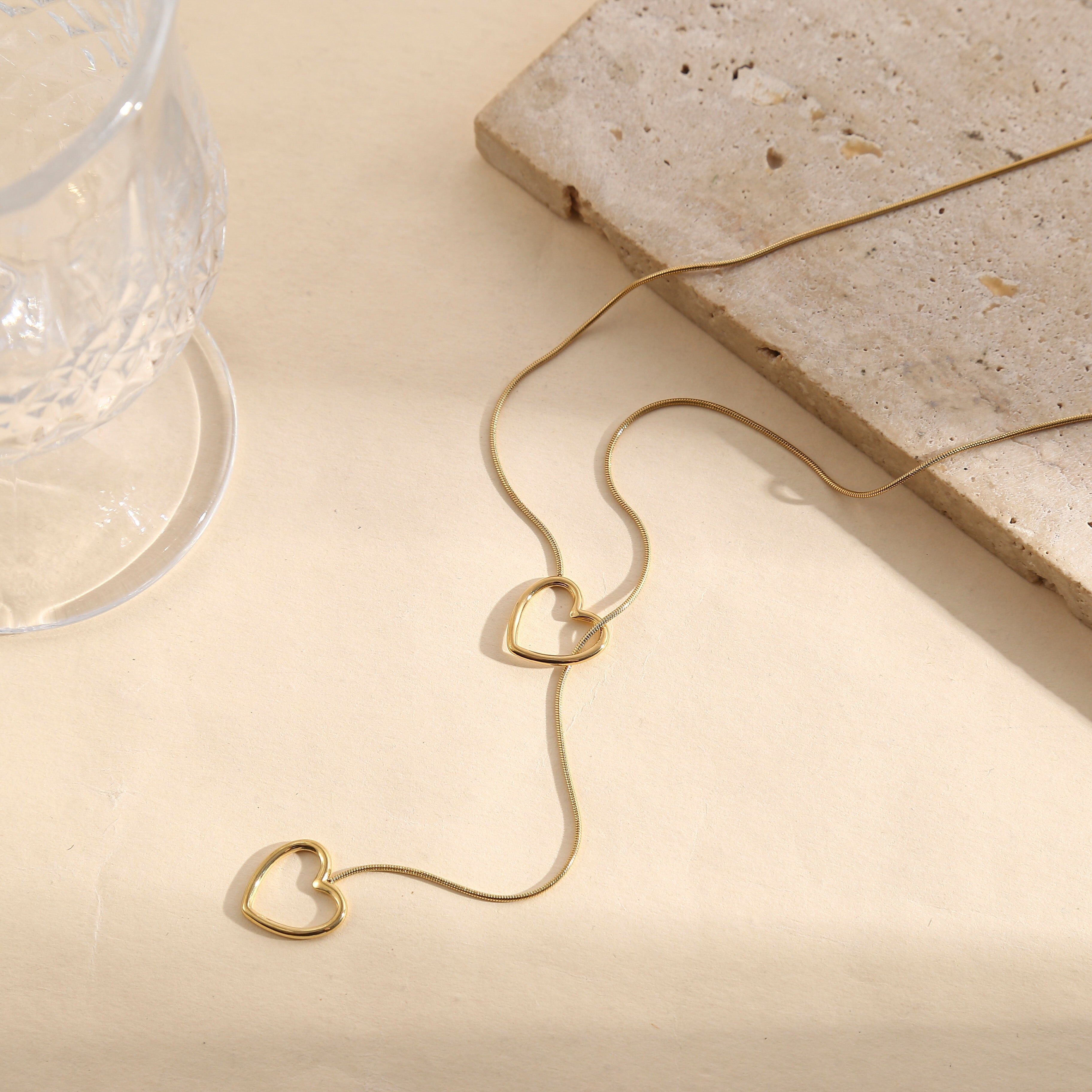 Collana in oro con una sottile catena a serpente rotonda e un doppio ciondolo a cuore traforato