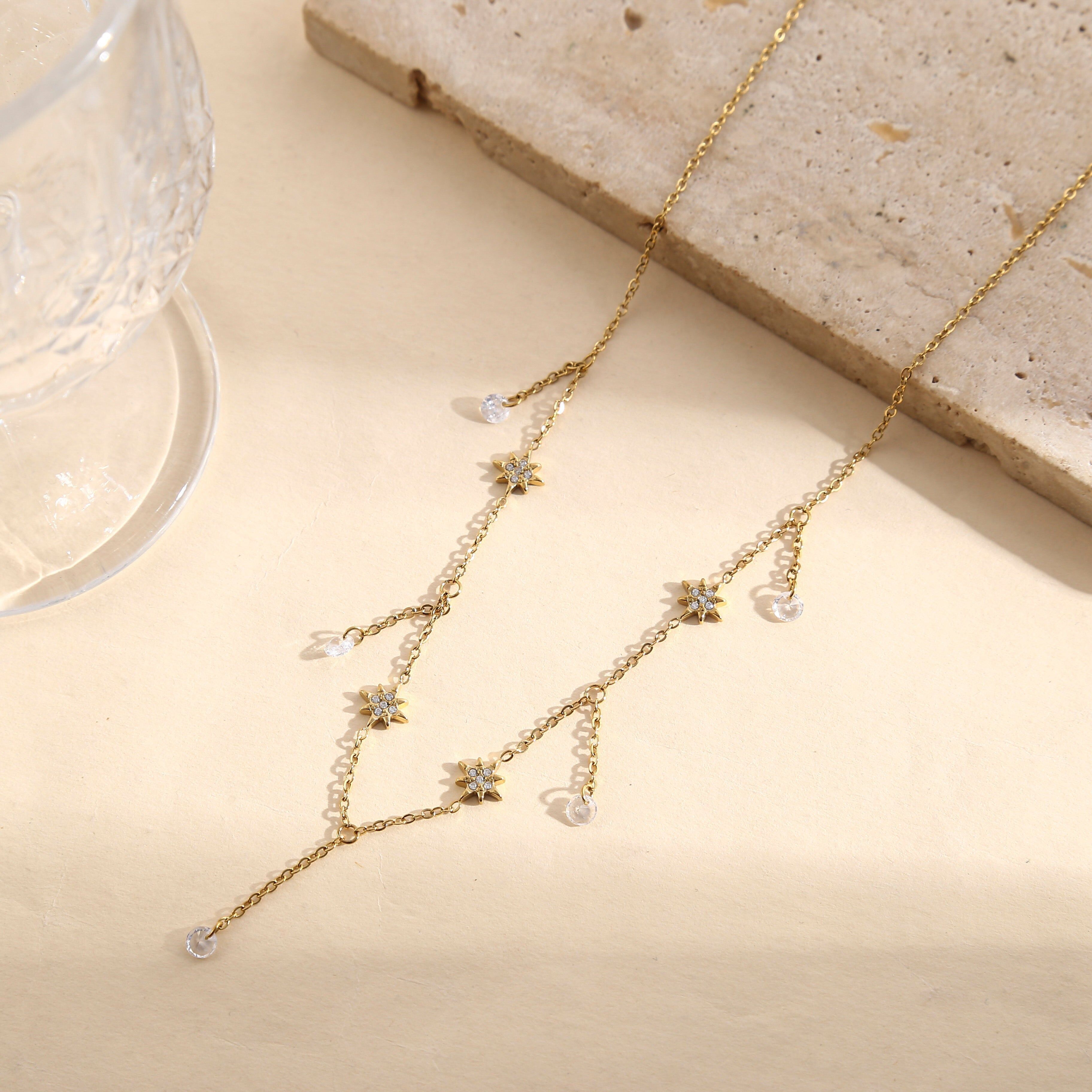 Collana color oro con catena sottile, nappe a forma di stella con strass e gocce di cristallo.