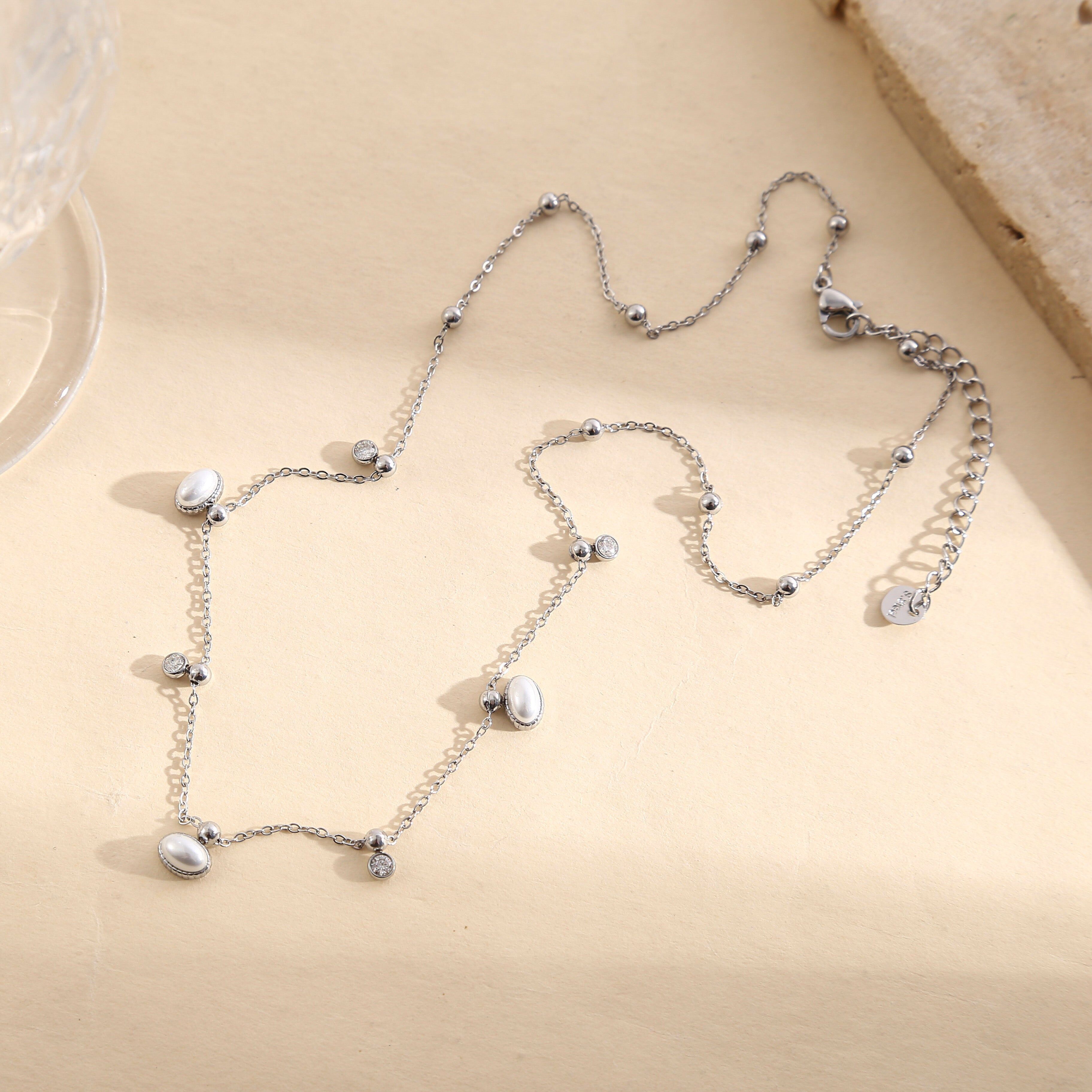 Collana in argento con catena sottile, perline dorate lisce e mini pendenti con strass.