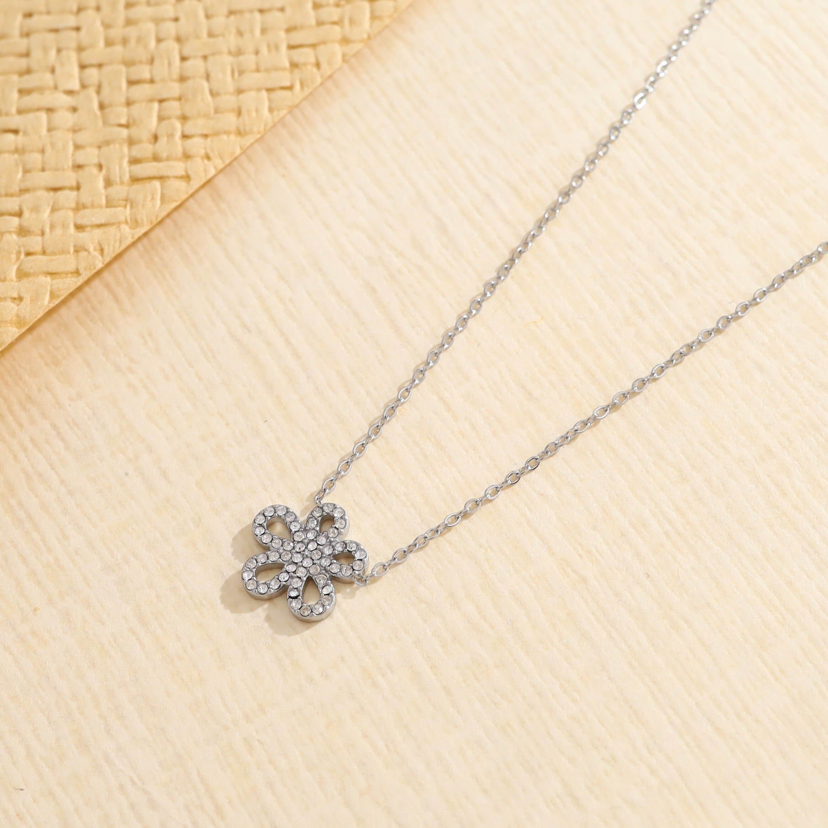 Collana in argento con una delicata catena e un ciondolo a forma di fiore con petali arrotondati e strass.