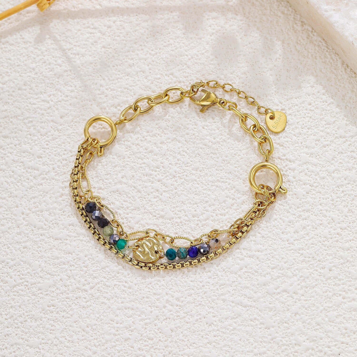 Bracciale placcato oro con più catene regolabili, pietre multicolori e un medaglione centrale martellato